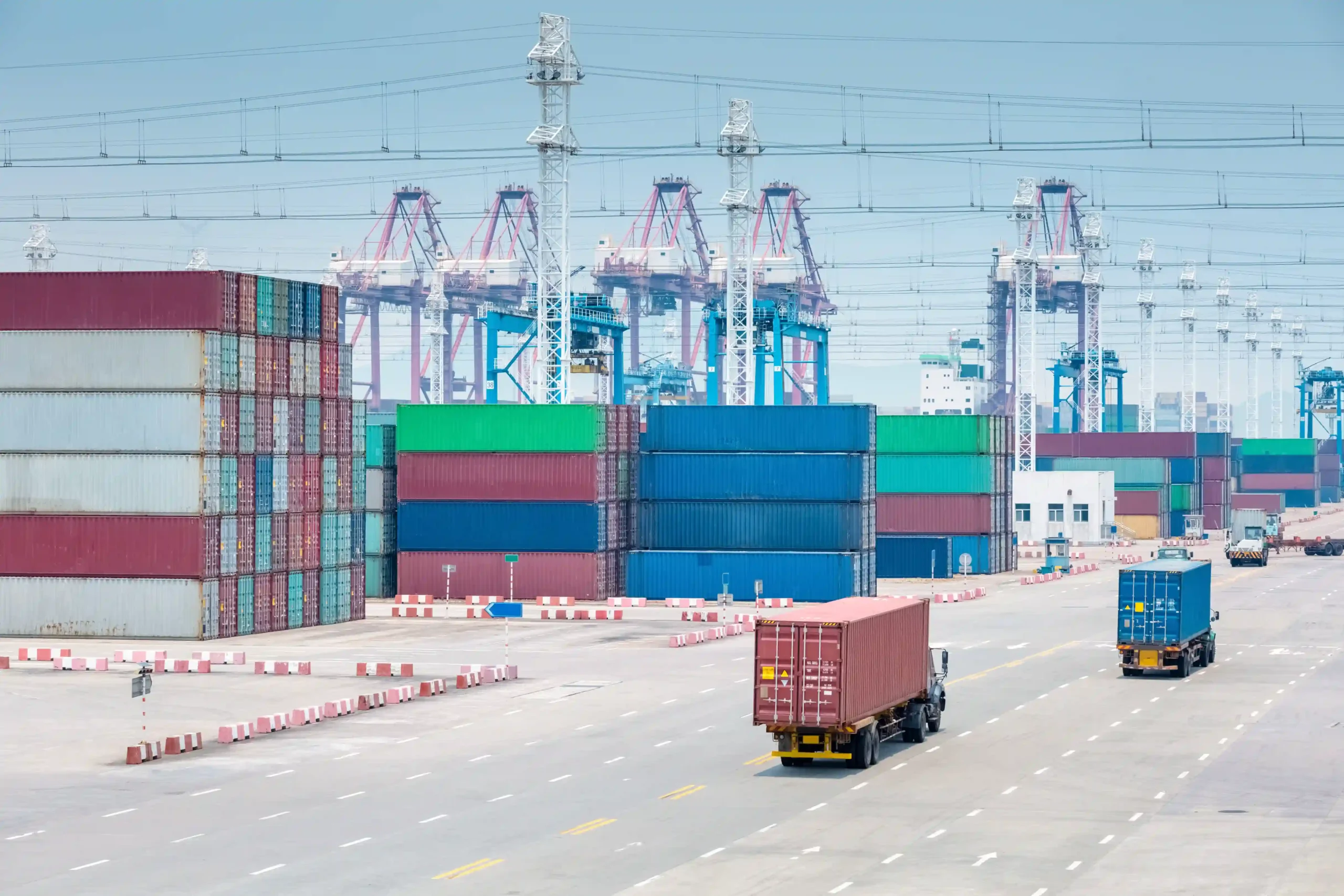 Trucks transporting shipping containers in a terminal under new de minimis release trade rules.