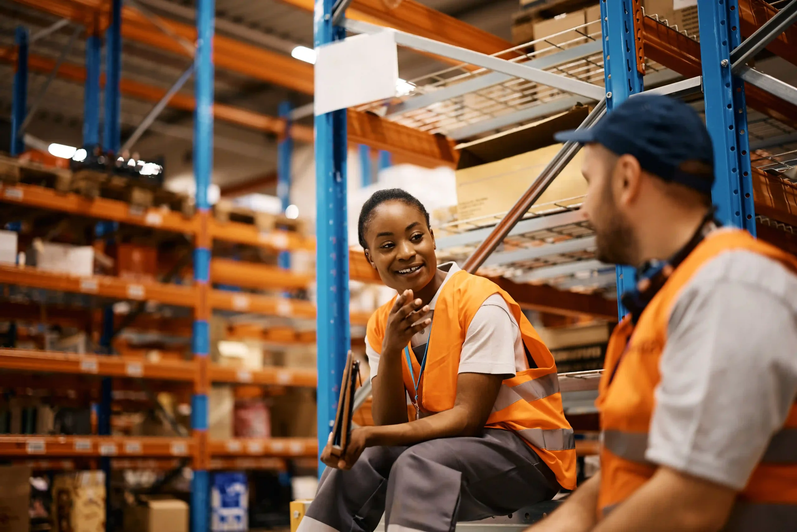 Warehouse employees in safety vests discussing compliance and teamwork, illustrating de minimis OSHA in practice.