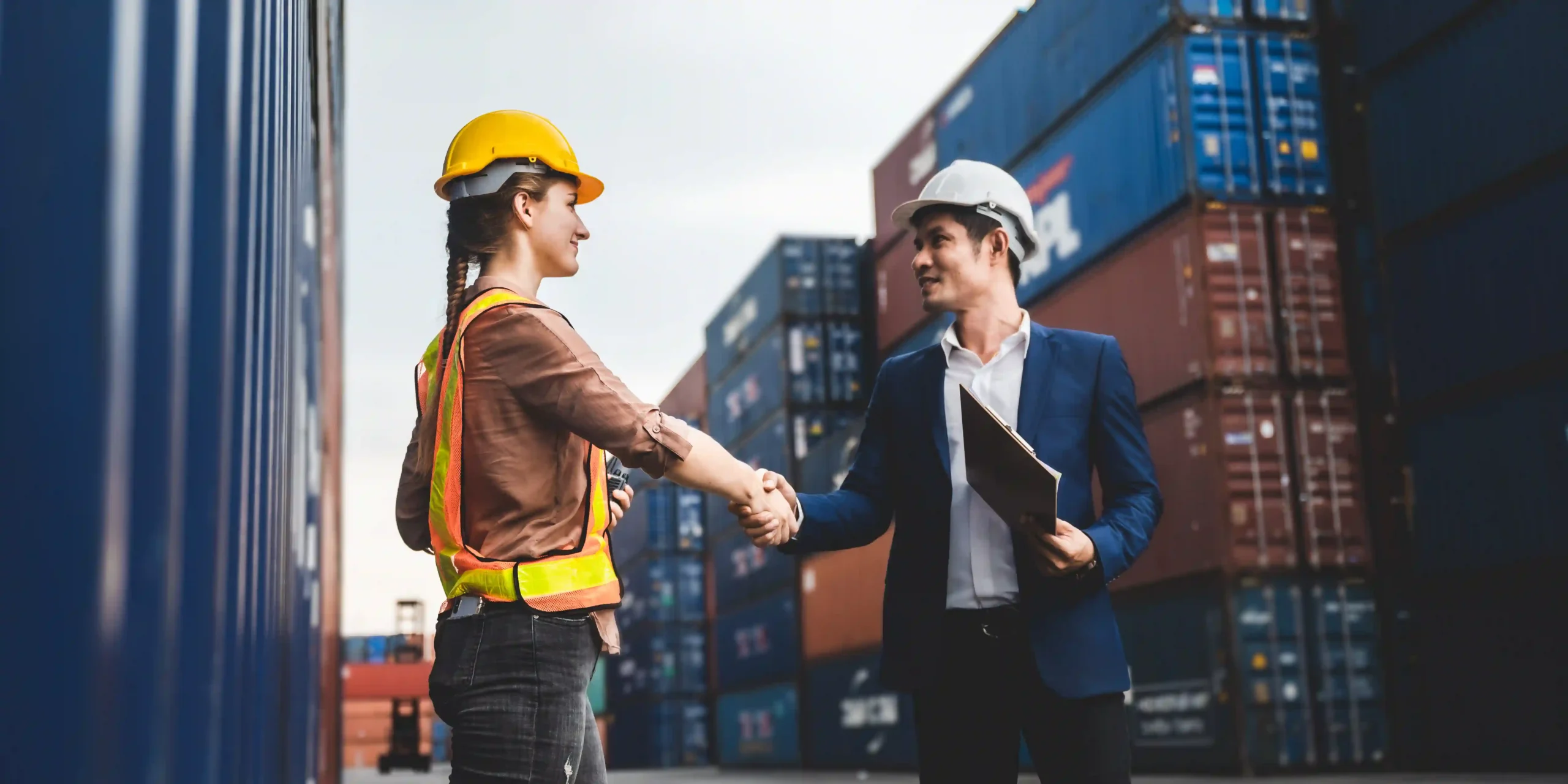 Logistics professionals finalizing trade agreements at a container yard while considering the de minimis limit in operations.