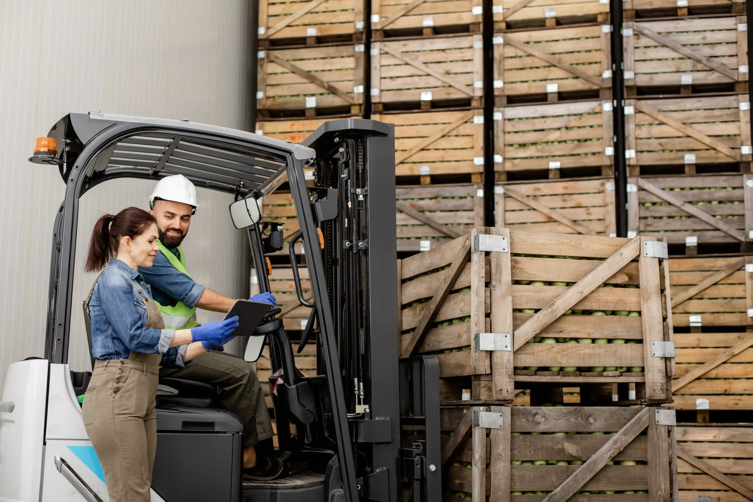 Forklift operator and supervisor reviewing documents on tablet, applying de minimis oid compliance in warehouse operations.