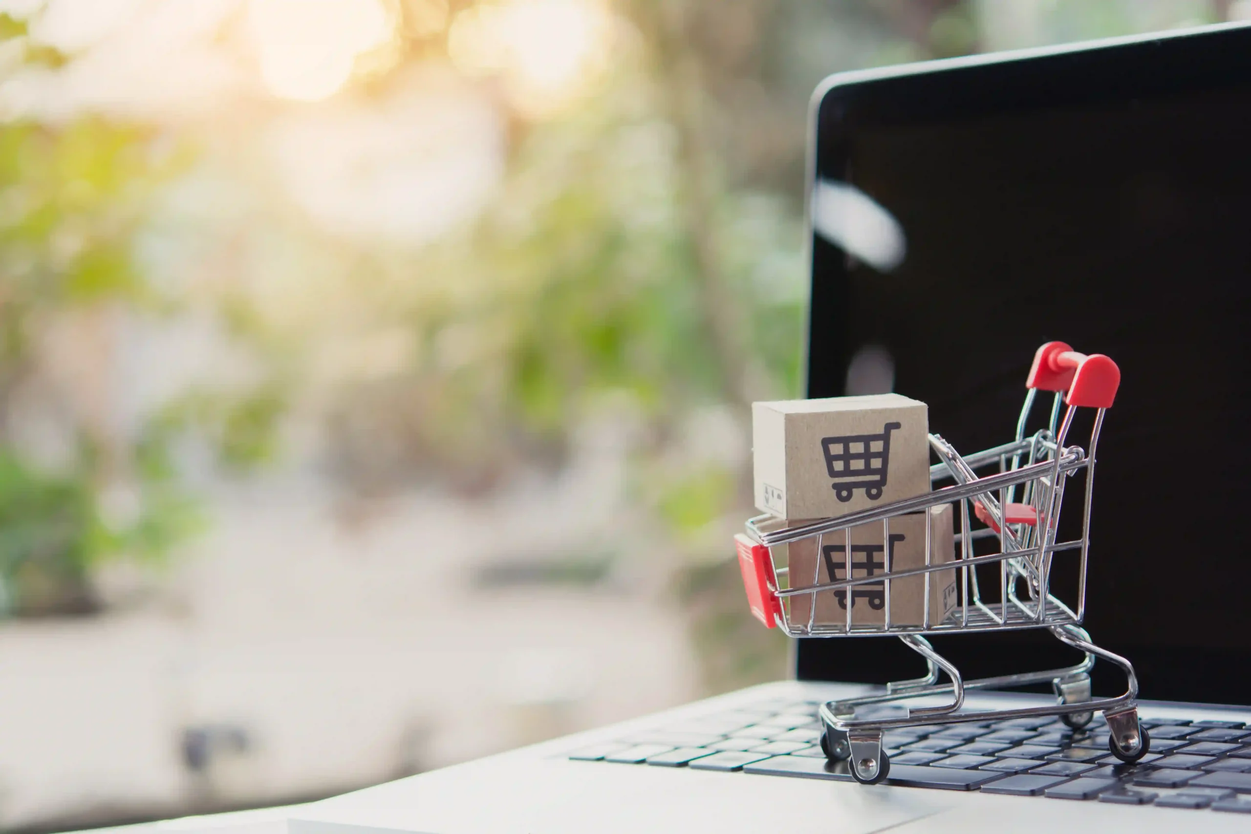 Mini shopping cart with parcel box on laptop keyboard symbolizing de minimis US e-commerce trade changes.