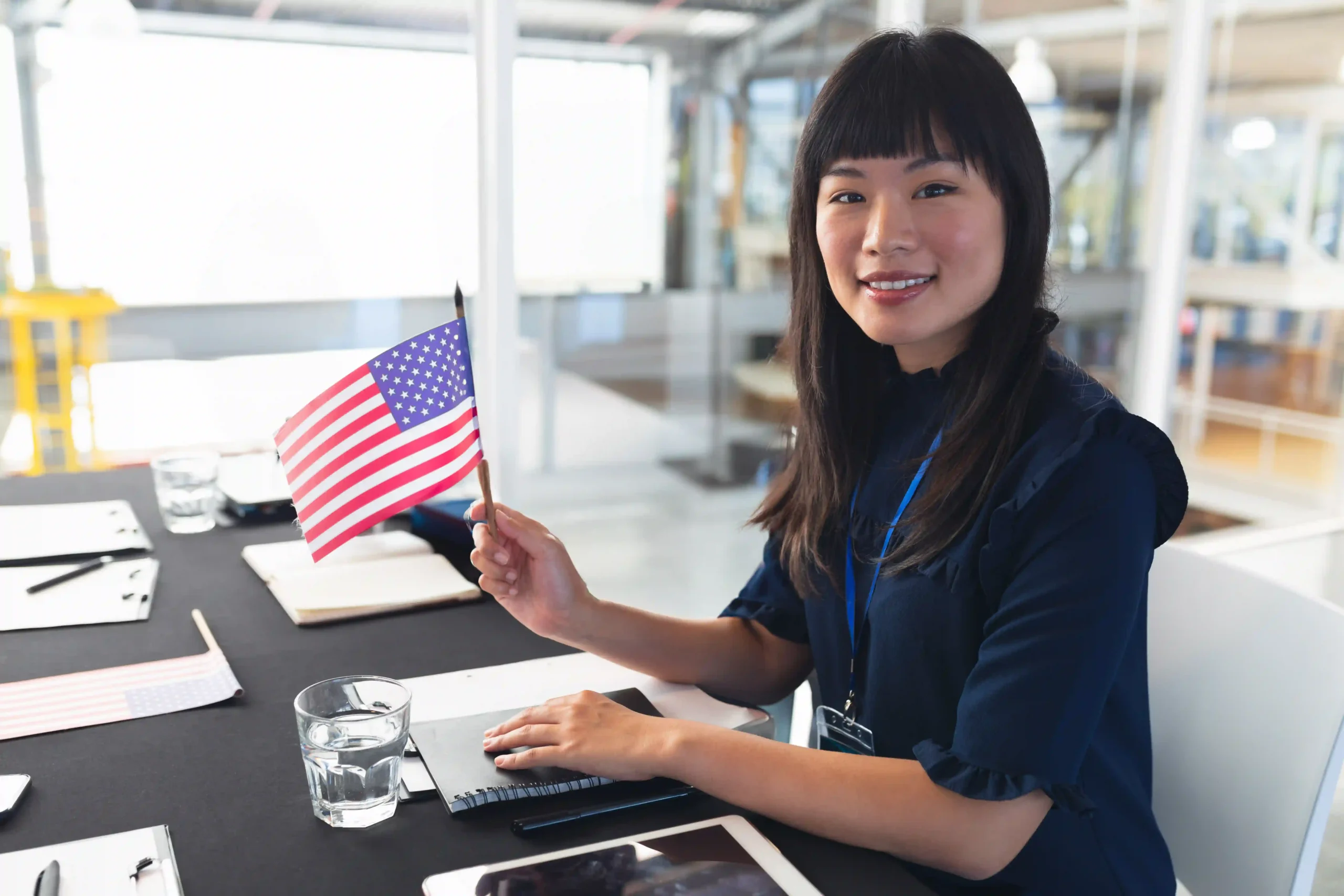 Business professional holding an American flag at a trade meeting discussing U.S. customs and de minimis entry policies.