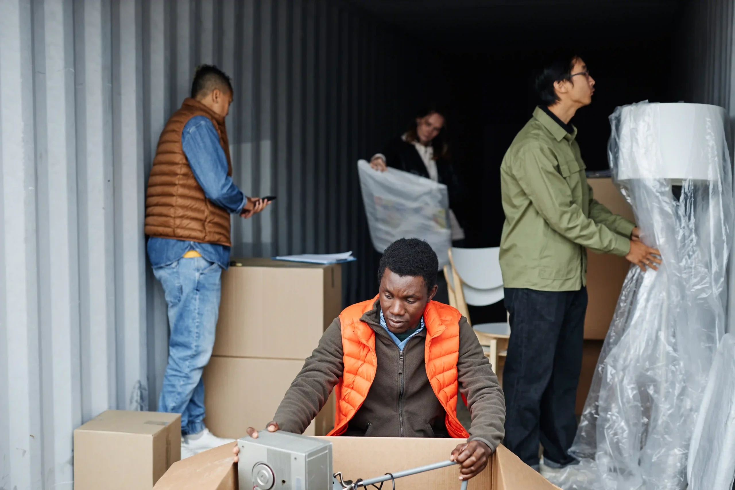 Workers unloading boxes from a shipping container, representing supply chain changes after de minimis rule imports adjustments.