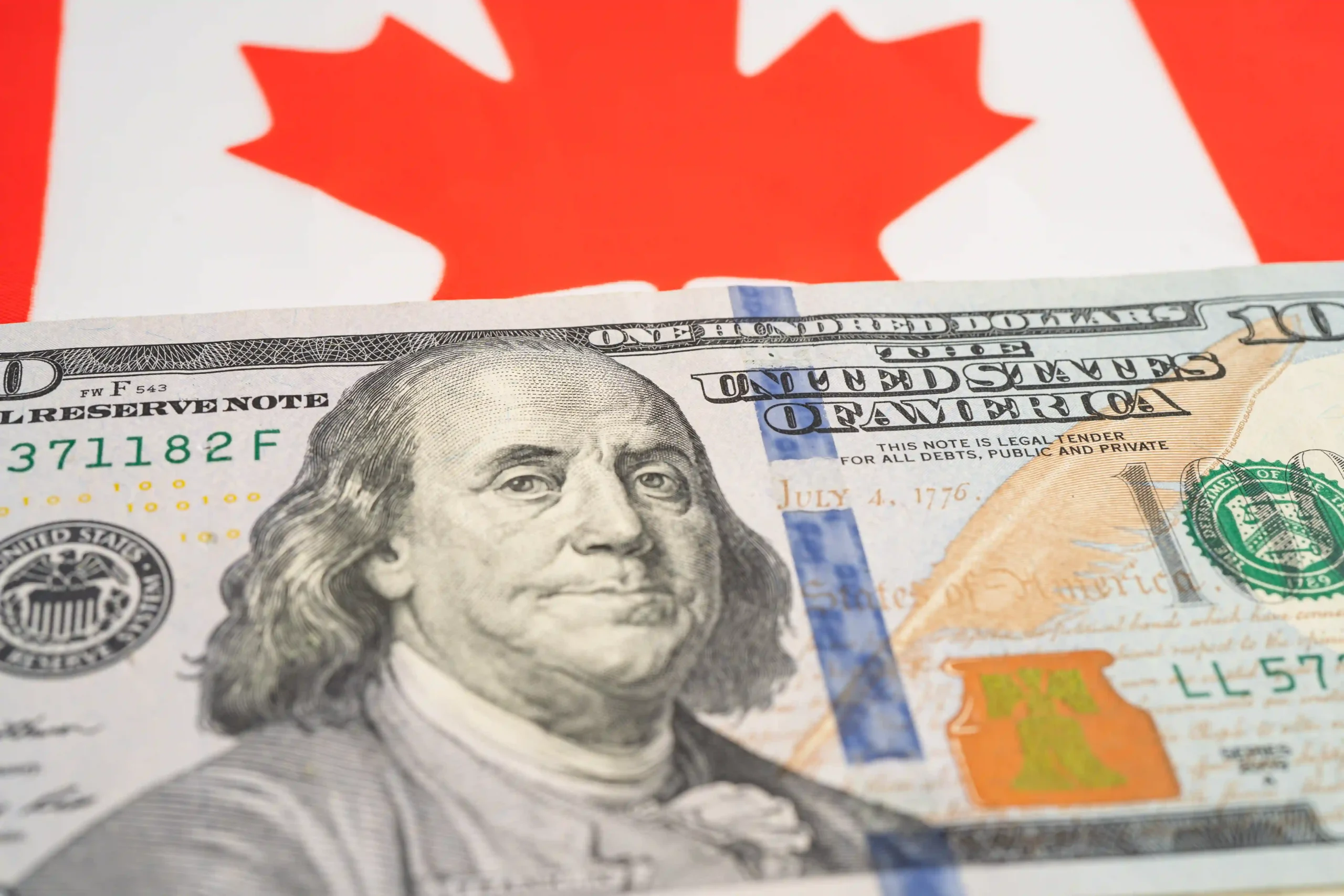 Close-up of Canadian flag and US dollar symbolizing financial impact of de minimis Canada to US rules.