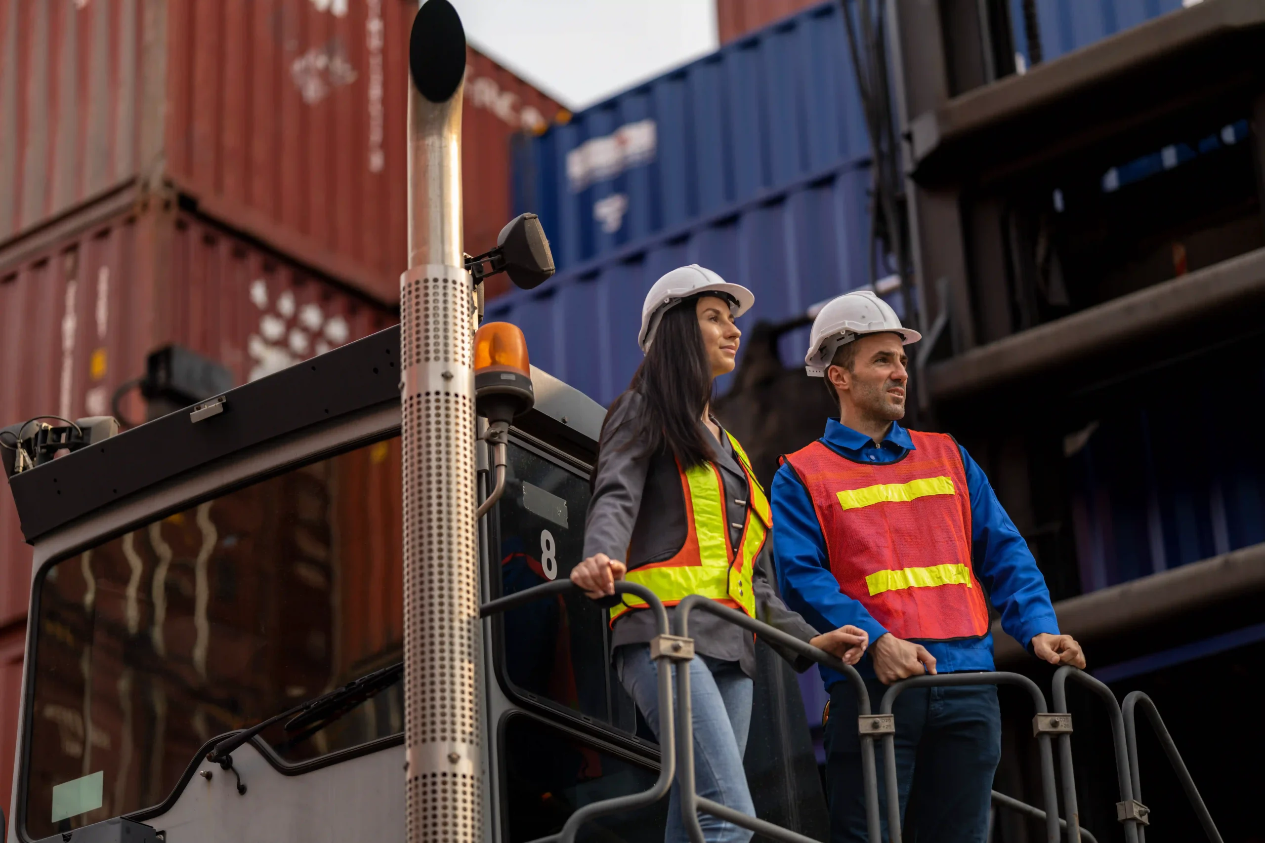 Logistics professionals in safety gear overseeing container operations, illustrating compliance with de minimis US customs rules.