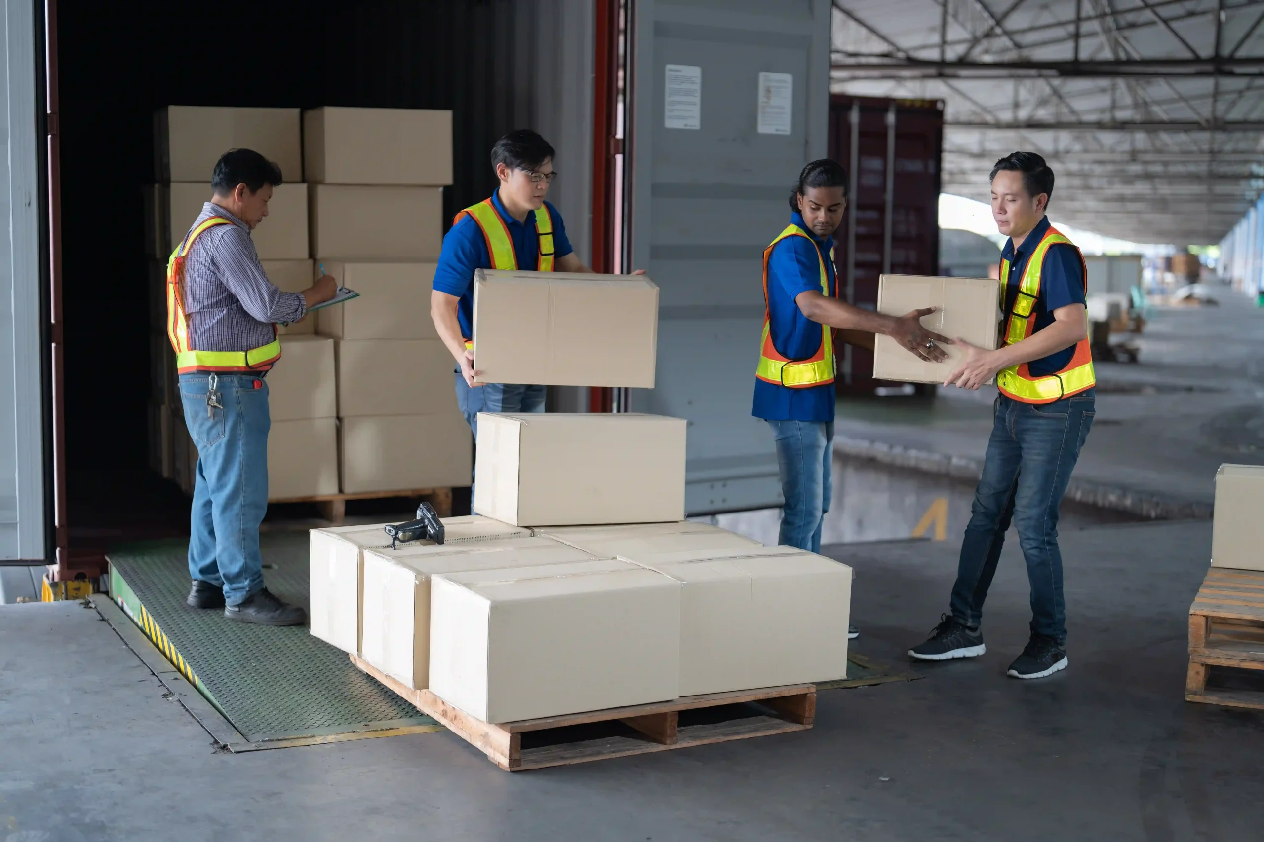 Cargo handlers unloading boxes from a shipping container as importers adapt to new rules on when is de minimis going away.