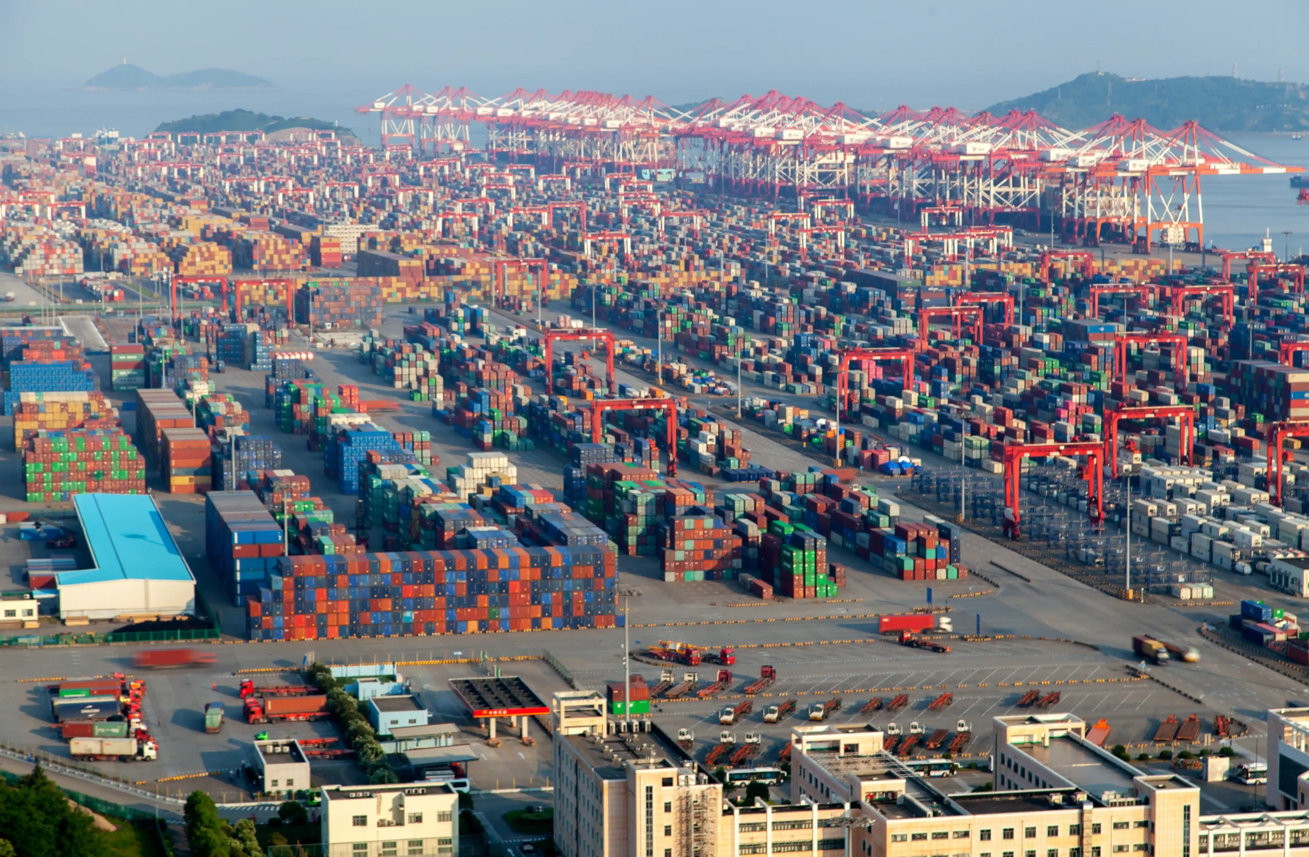 Aerial view of a busy international port filled with shipping containers, illustrating FTZ benefits for e-commerce sellers through streamlined import logistics.