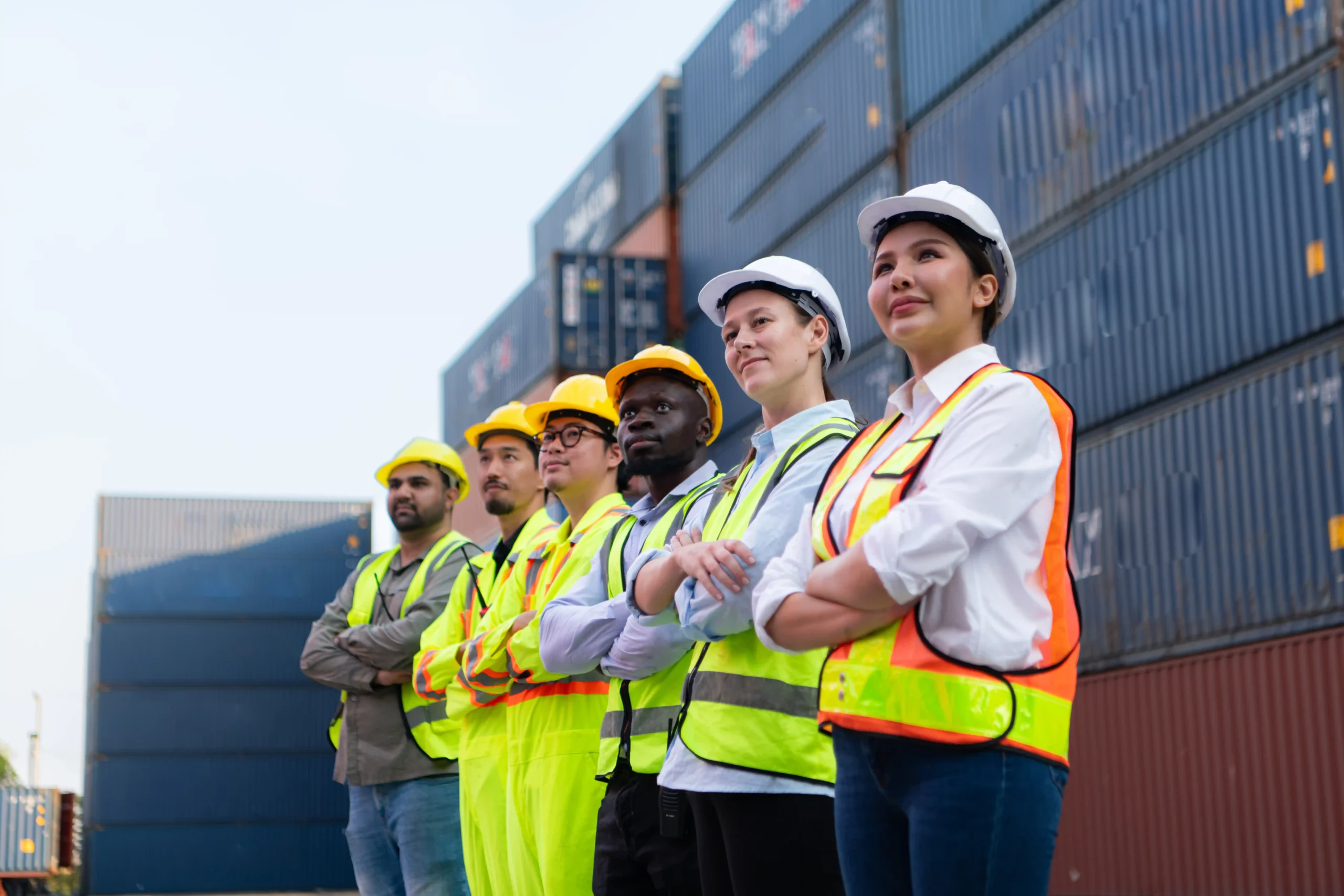 Logistics workers standing at a shipping yard, representing how the cost of new customs rules 2025 impacts import operations.