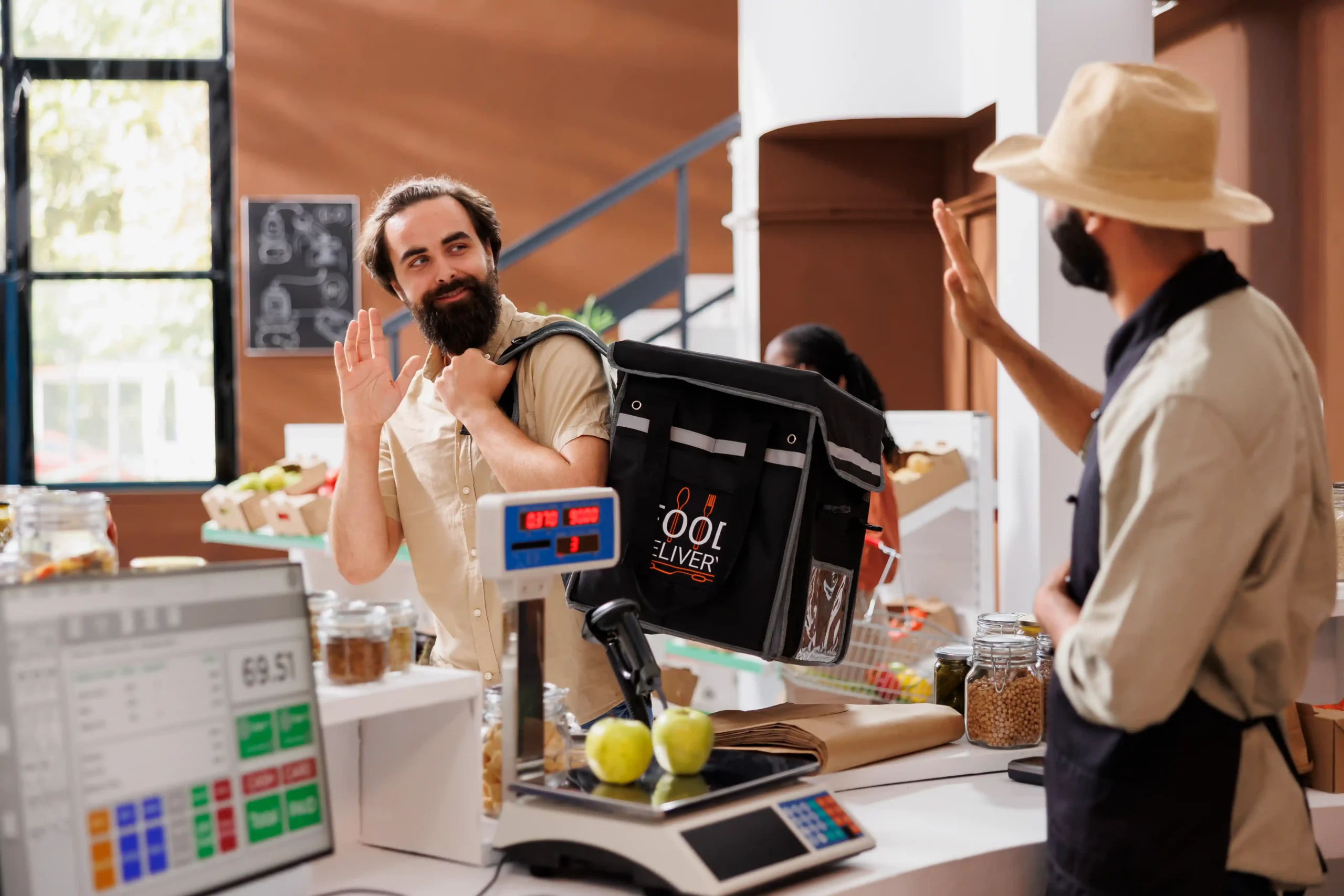 A delivery courier waving goodbye to a cashier in a retail store, representing last-mile delivery and fulfillment changes following de minimis end 2025.