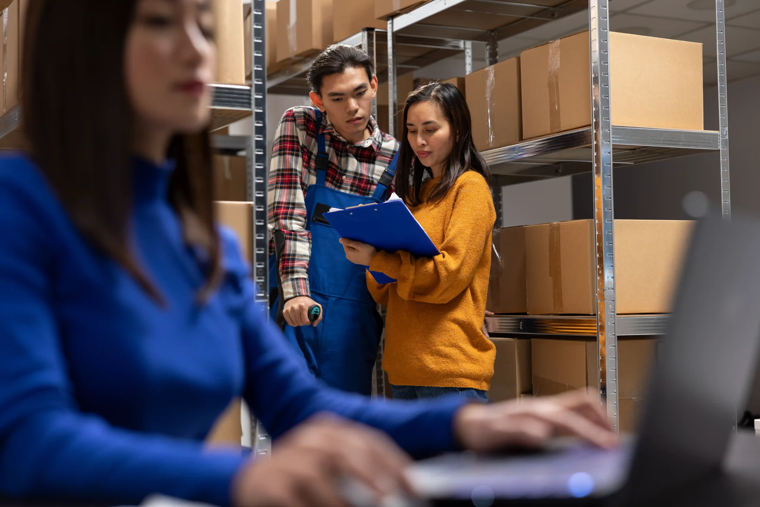 Asian warehouse staff reviewing inventory documents together to track accuracy and improve kpi for warehouse and logistics.