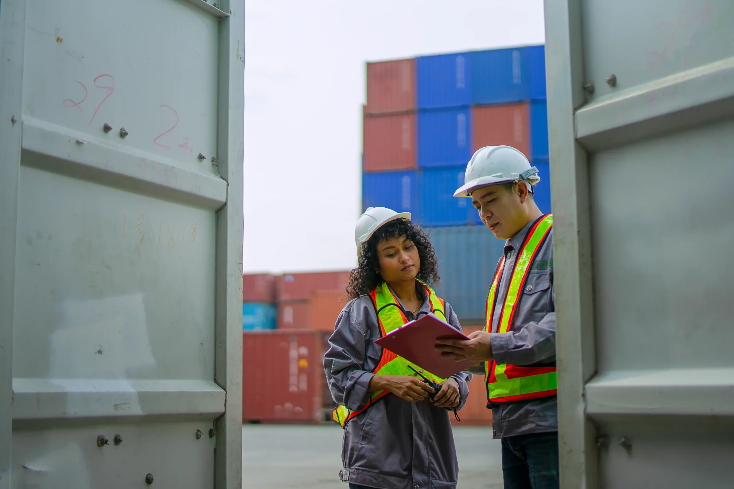 Workers reviewing cargo and documentation inside a container yard as part of a global warehouse and logistics operation