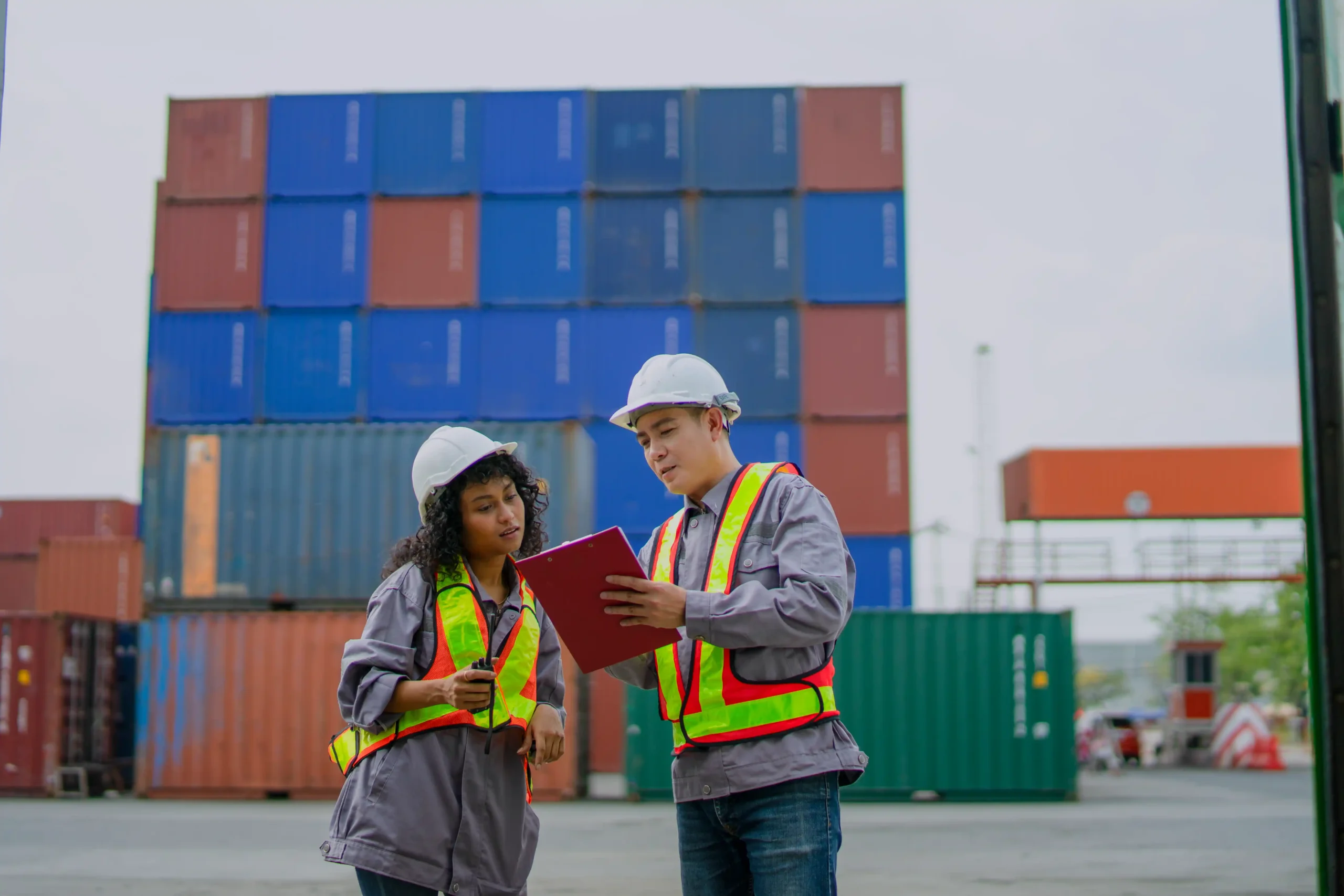 Logistics professionals reviewing shipment documentation at a container yard, explaining are logistics and supply chain the same in real-world operations