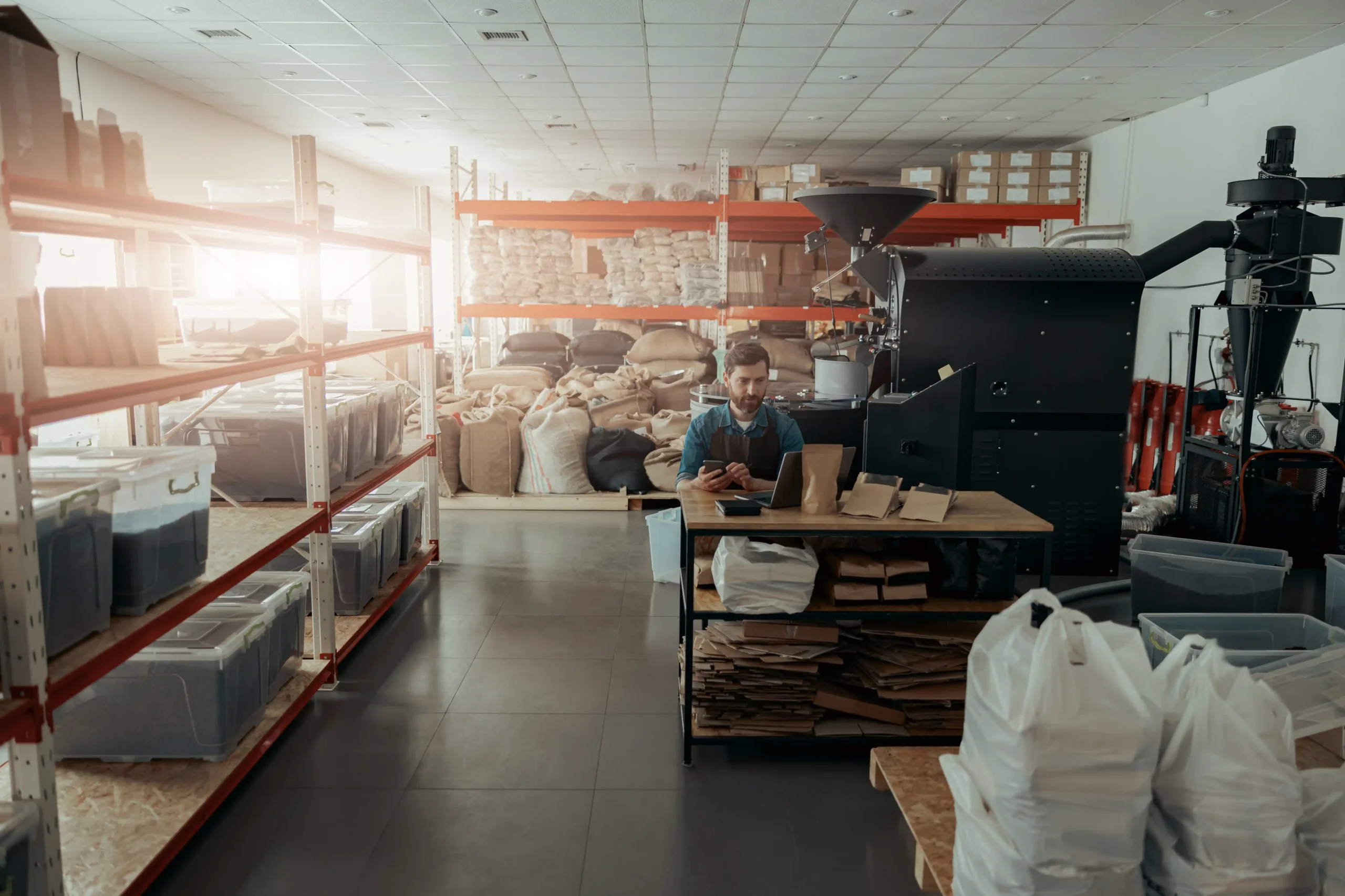 A worker managing inventory inside a compact warehouse with shelving and packaging materials, demonstrating how little warehouse storage supports daily operations.