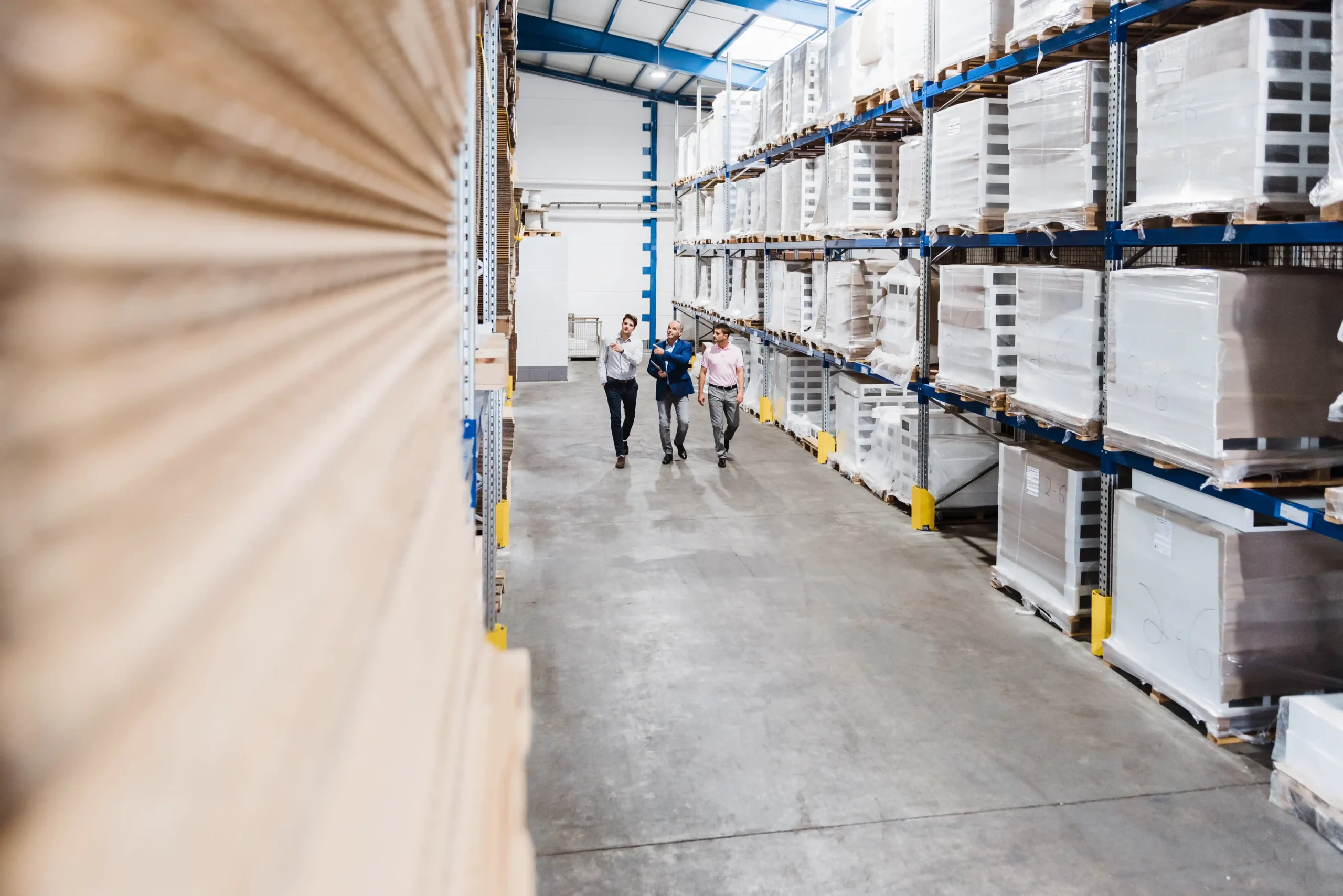 Business leaders walking through a modern warehouse discussing operations and warehouse and logistics news impacting supply chains
