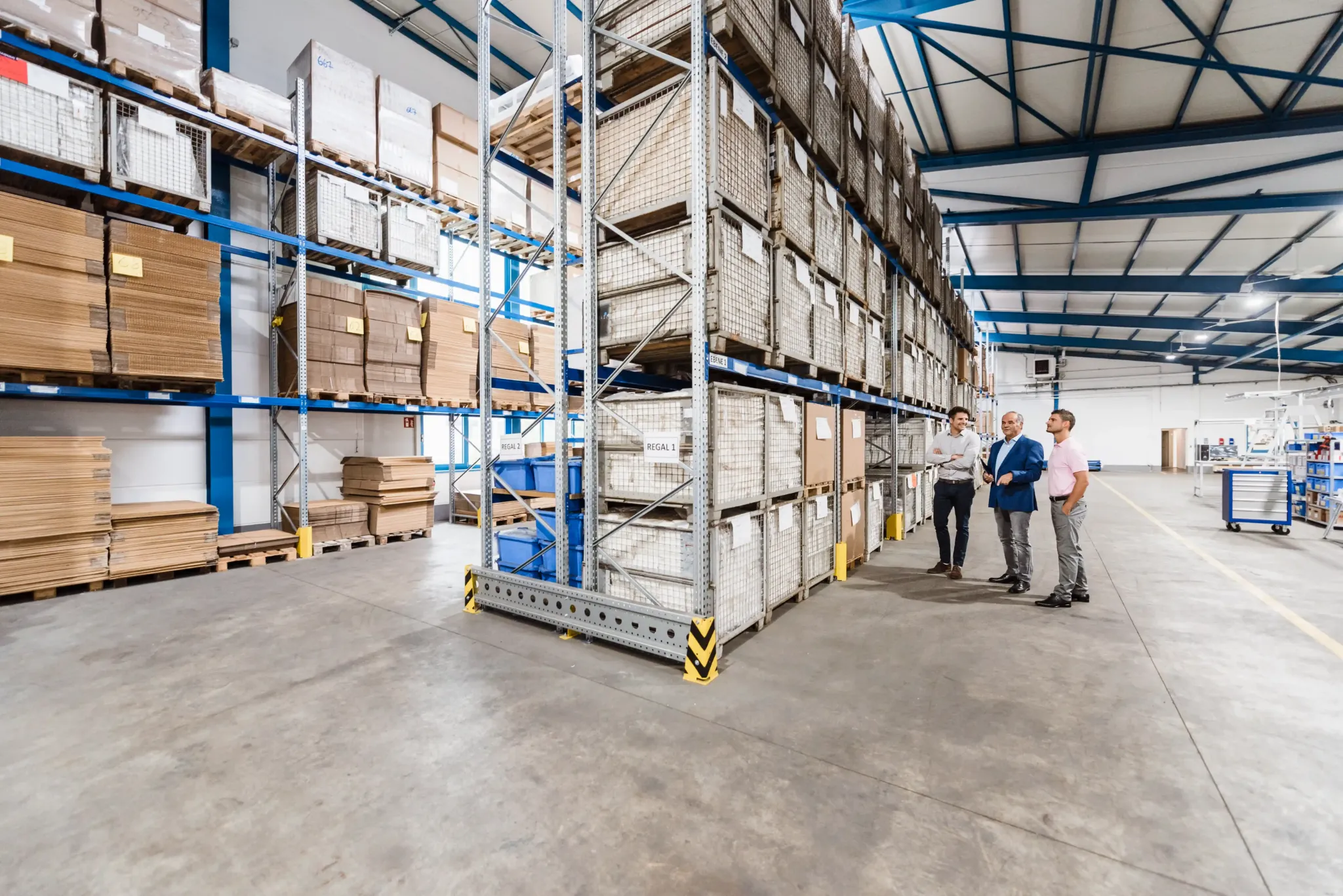 Business team reviewing warehouse and storage services inside a large organized facility with high pallet racks.