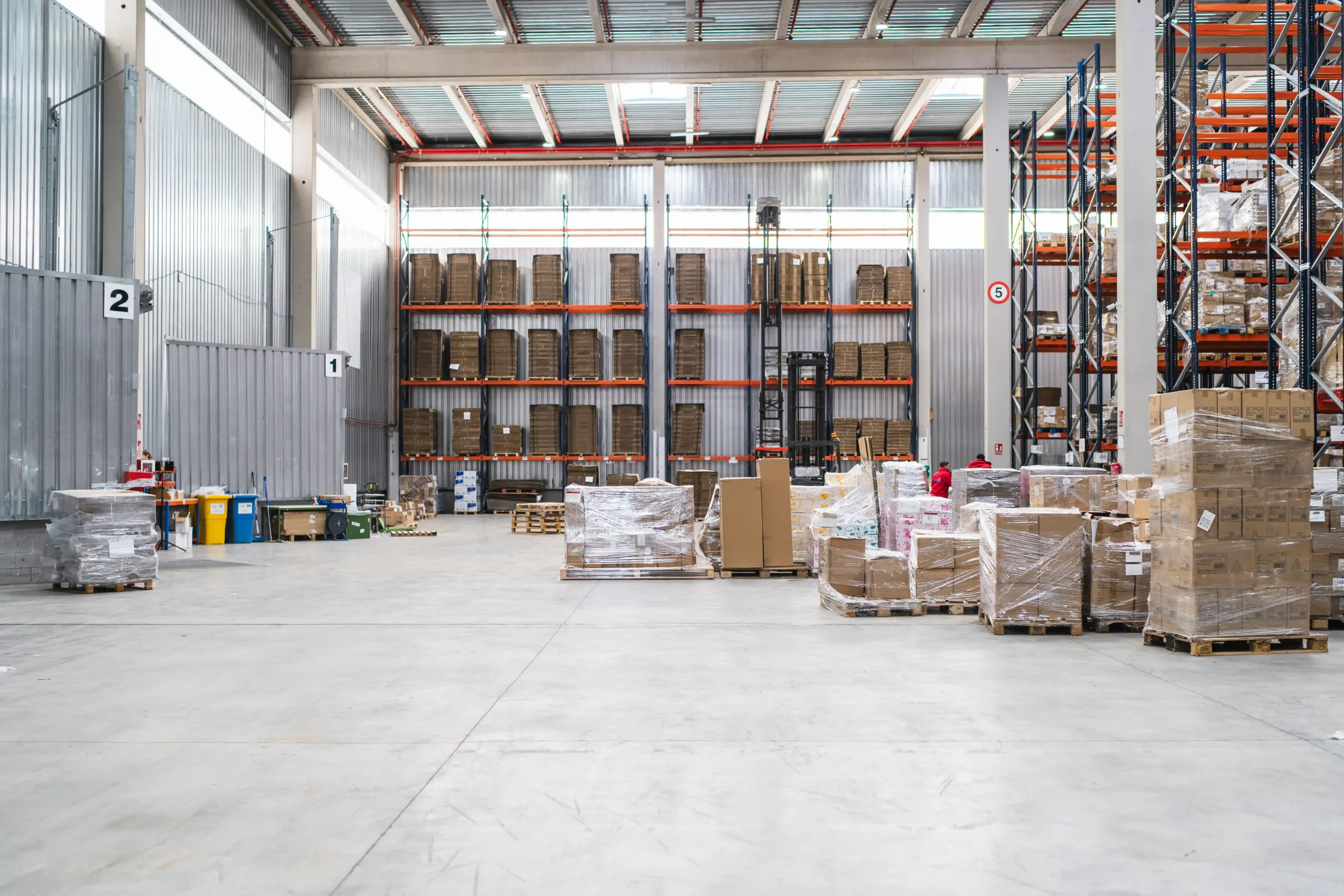 Interior of a modern distribution center with stacked pallets and organized storage, showing what efficient small warehouse units for rent can look like.