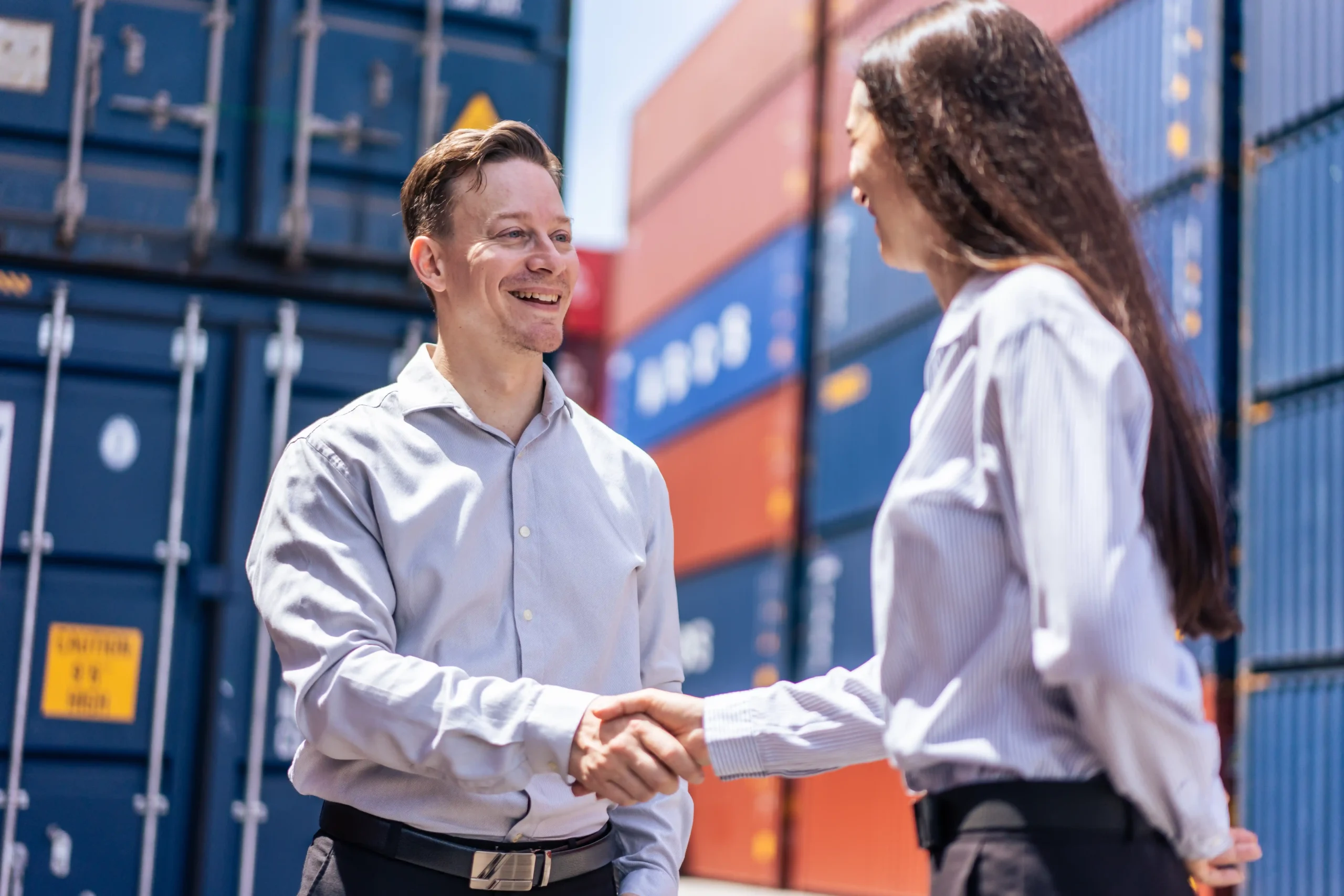 Business professionals shaking hands at a container terminal representing trust in global warehouse and logistics services