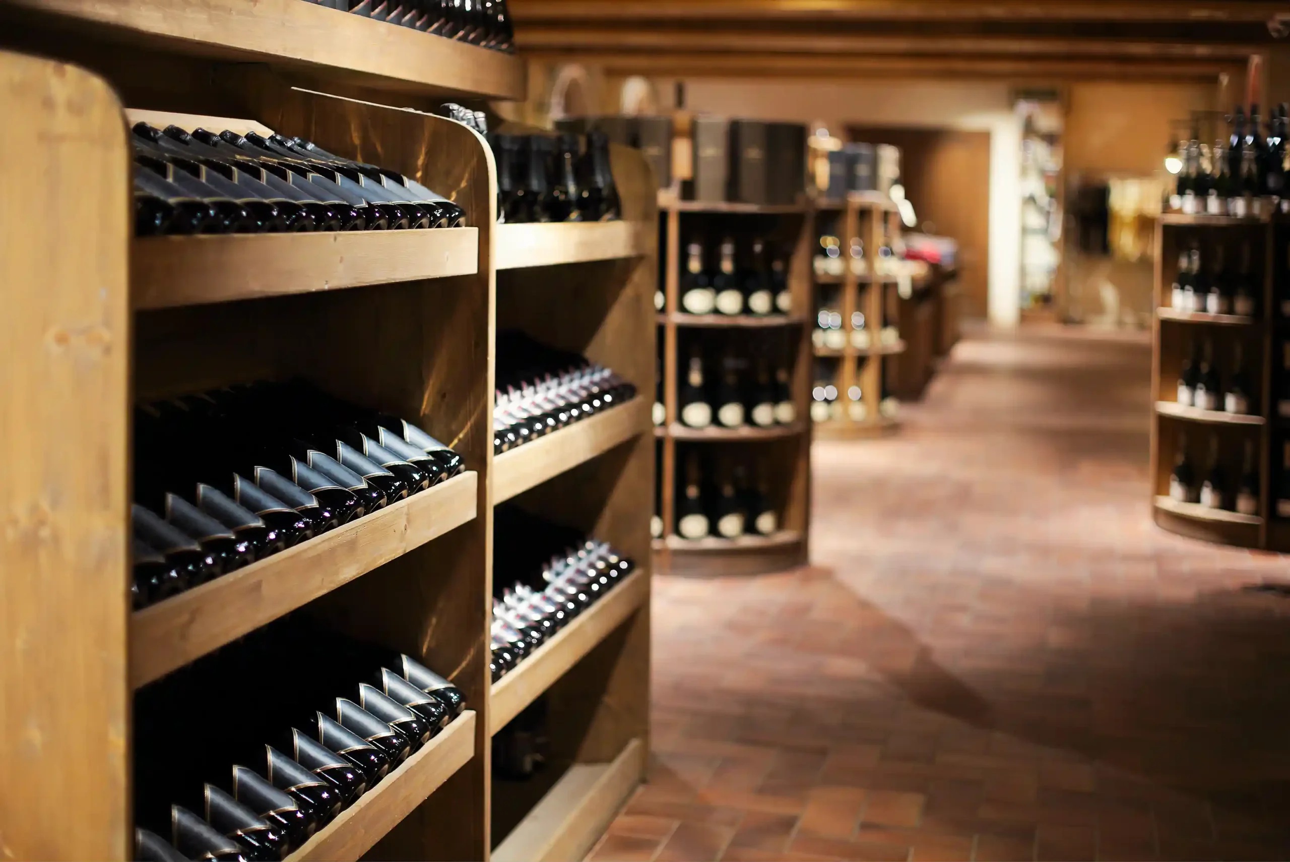 A neatly organized commercial wine storage cellar with wooden racks holding rows of champagne and wine bottles in a temperature-controlled environment.