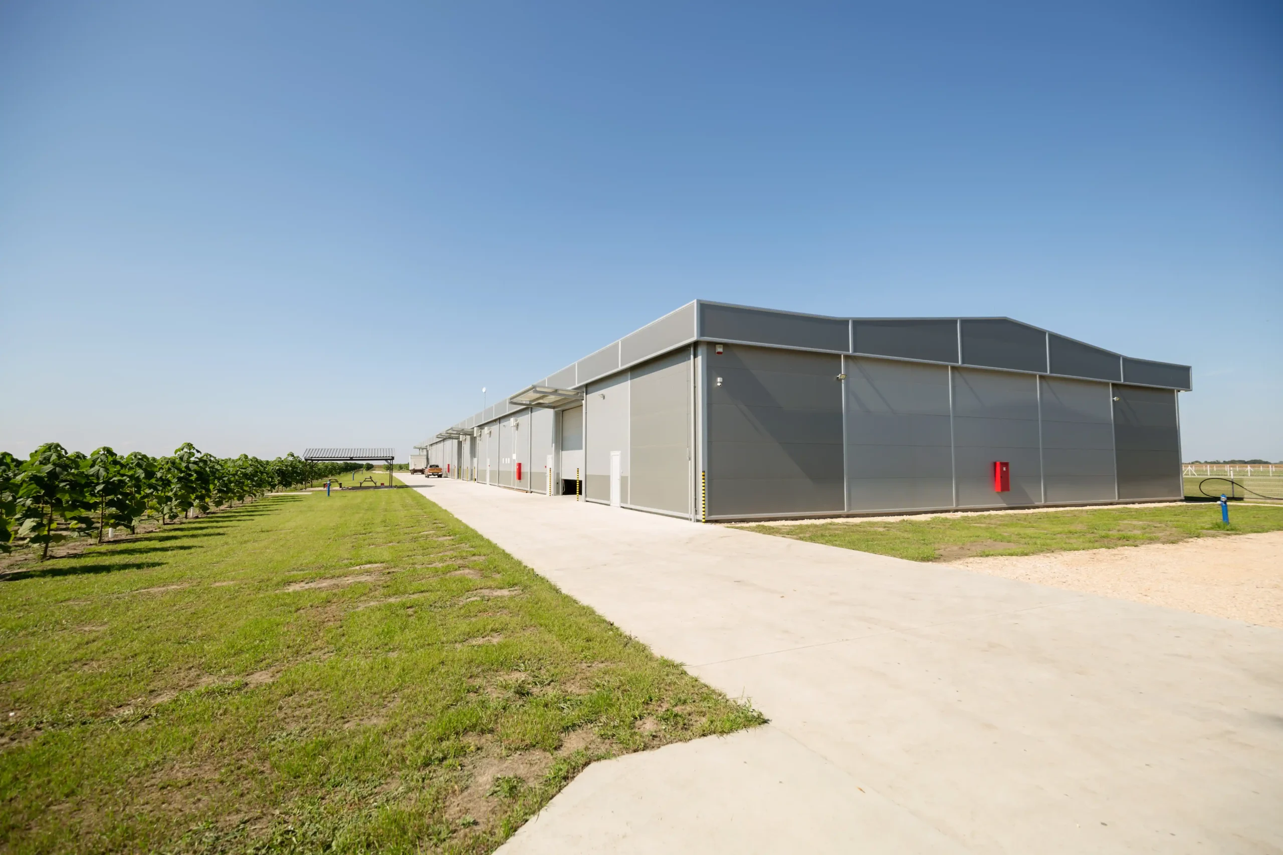 Modern warehouse storage buildings with steel exterior panels and wide access paths on a clear day.