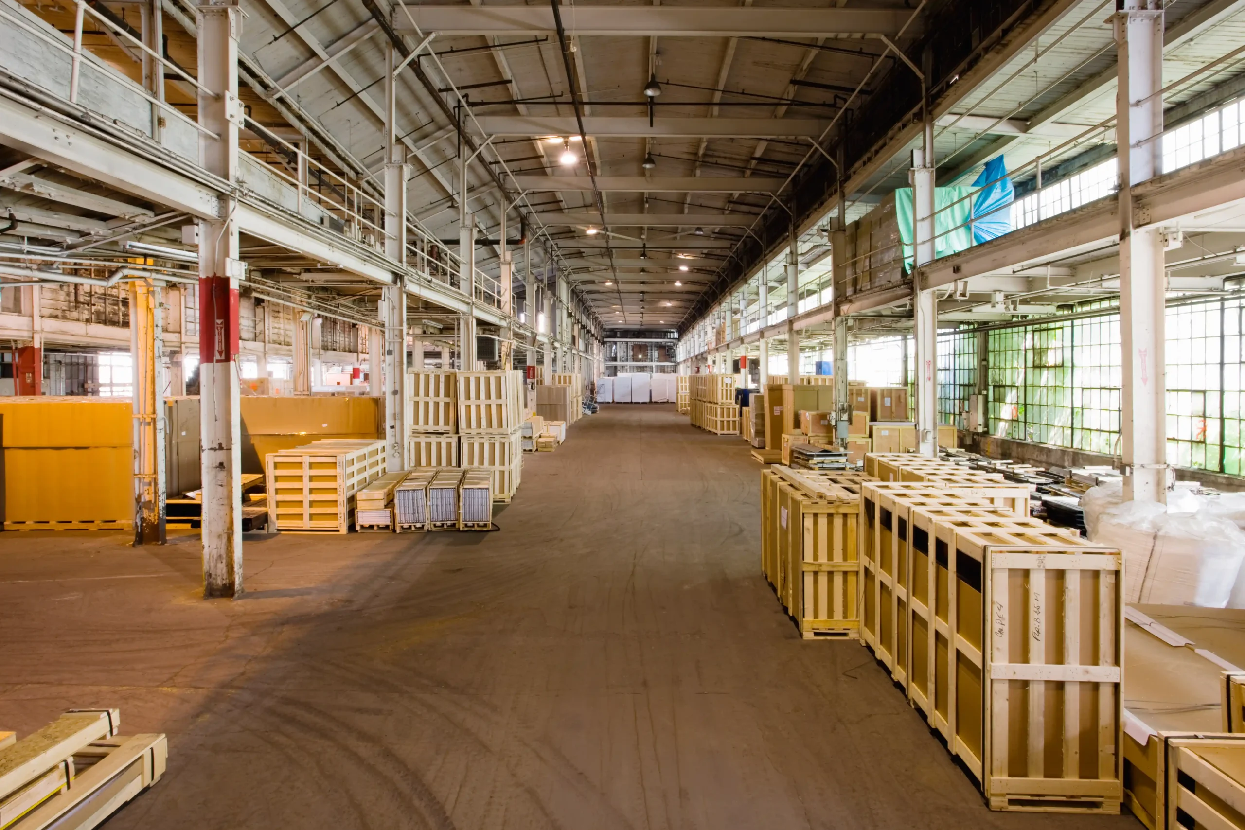 A large warehouse storage facility filled with wooden crates and bulk inventory organized along wide aisles.