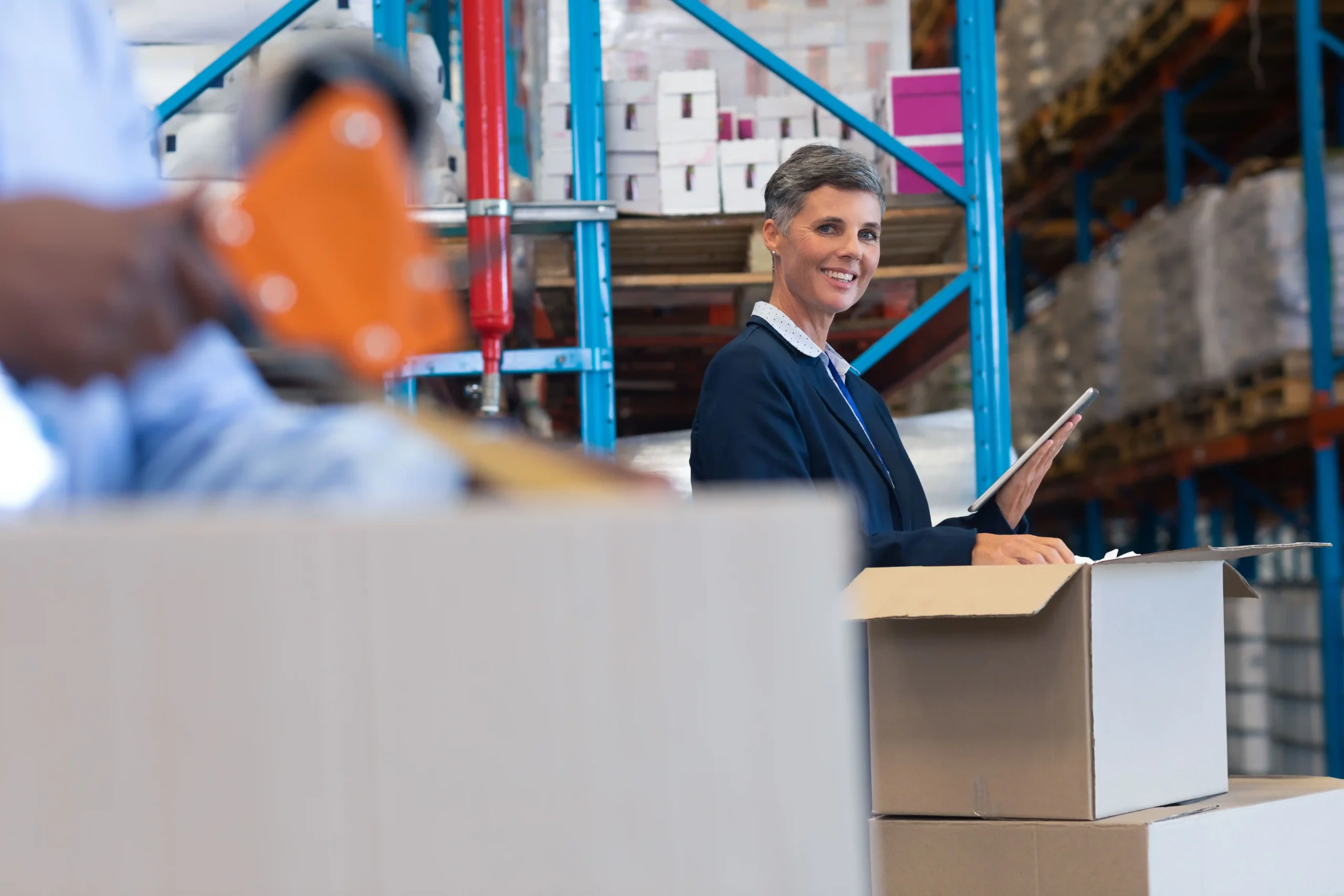 A warehouse supervisor smiling while managing packing tasks, representing how an automated warehouse storage system improves accuracy and workflow visibility.