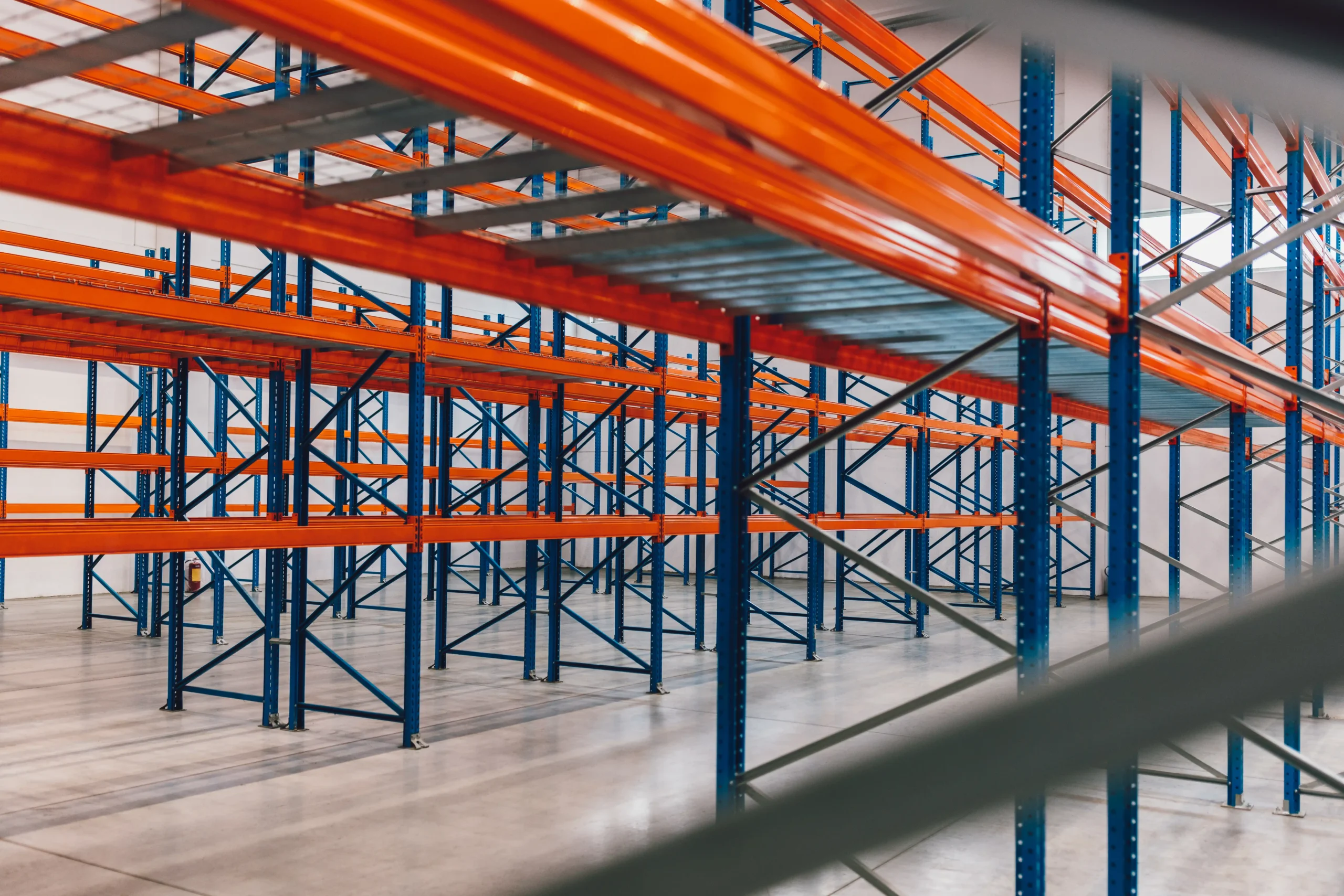 Empty warehouse showing newly installed metal racks for warehouse storage with steel beams and open aisles.