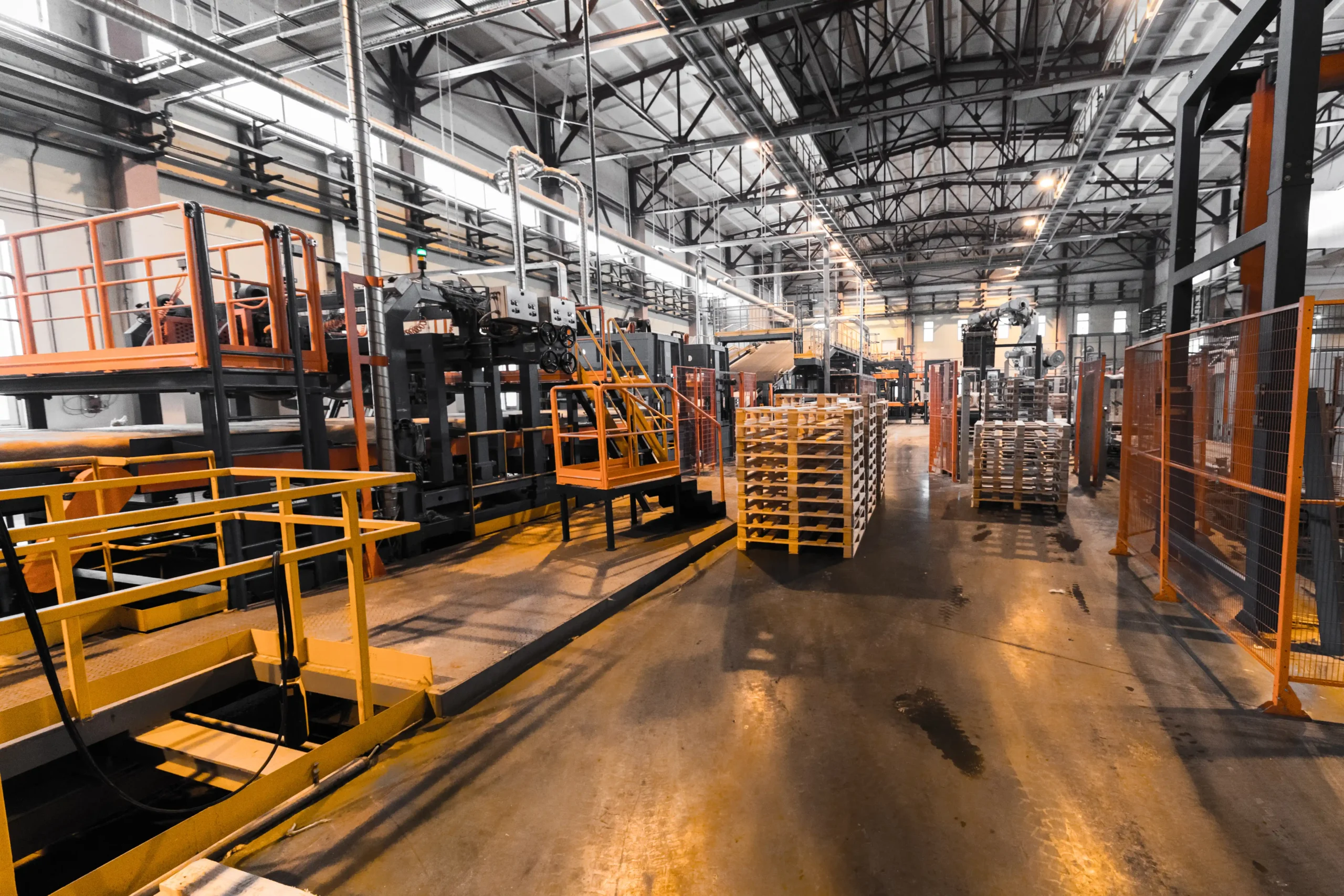 Interior of an industrial warehouse with machinery and pallet stacks used to support short term warehouse storage and flexible inventory needs.