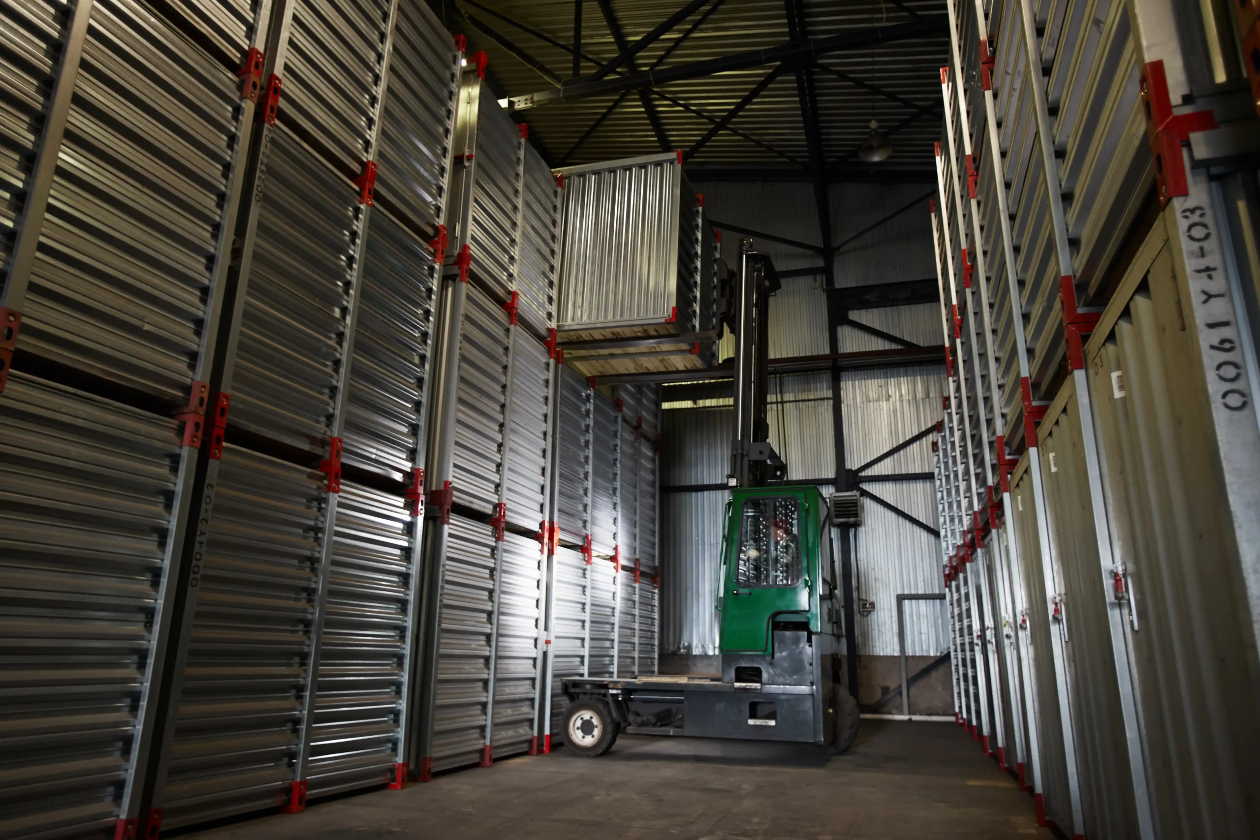 Forklift placing containers on tall industrial racks inside a facility optimized for small warehouse storage and maximum vertical capacity.