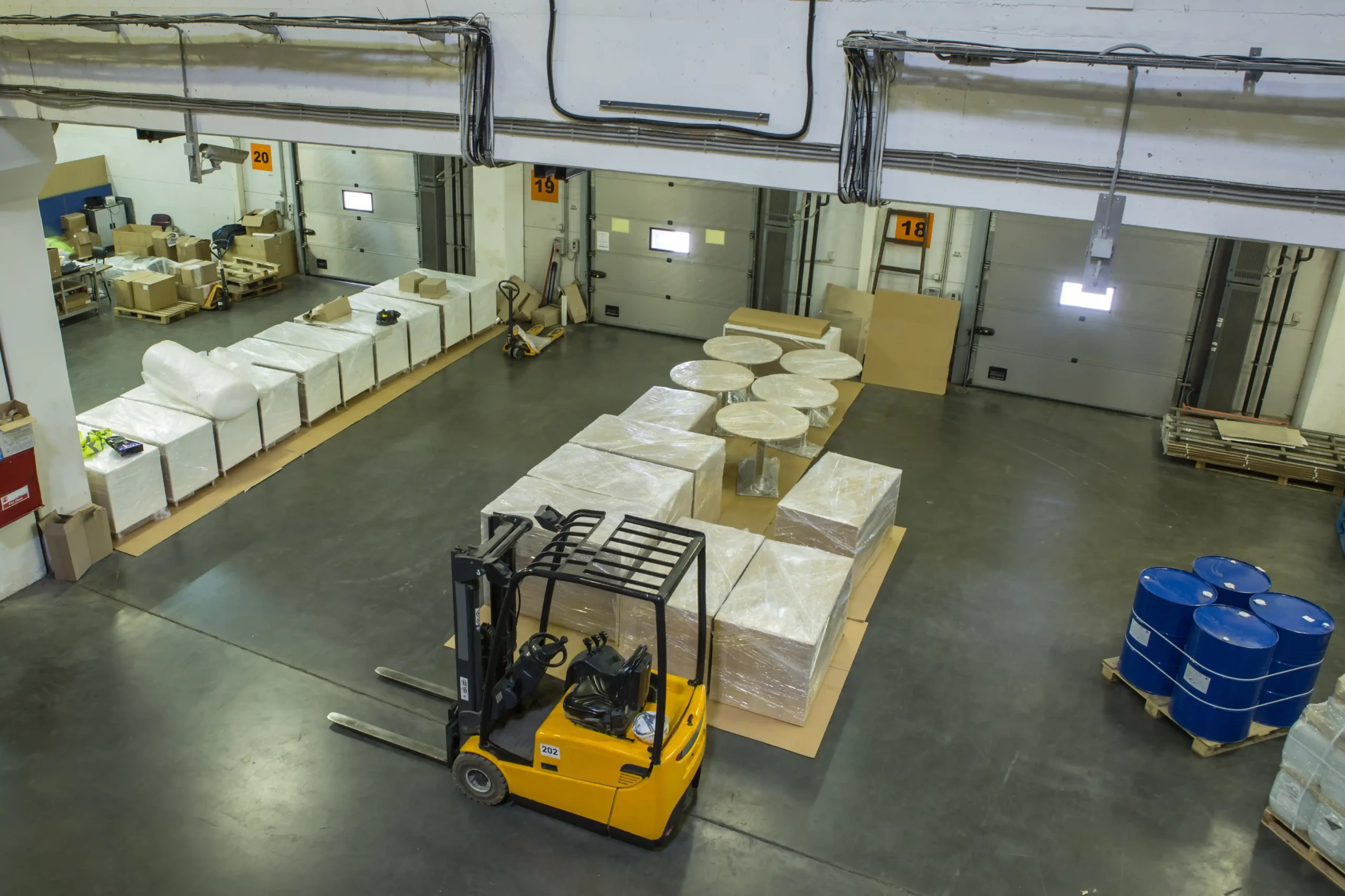 An overhead view of a warehouse receiving area with pallets and equipment arranged using small warehouse storage ideas to improve workflow.