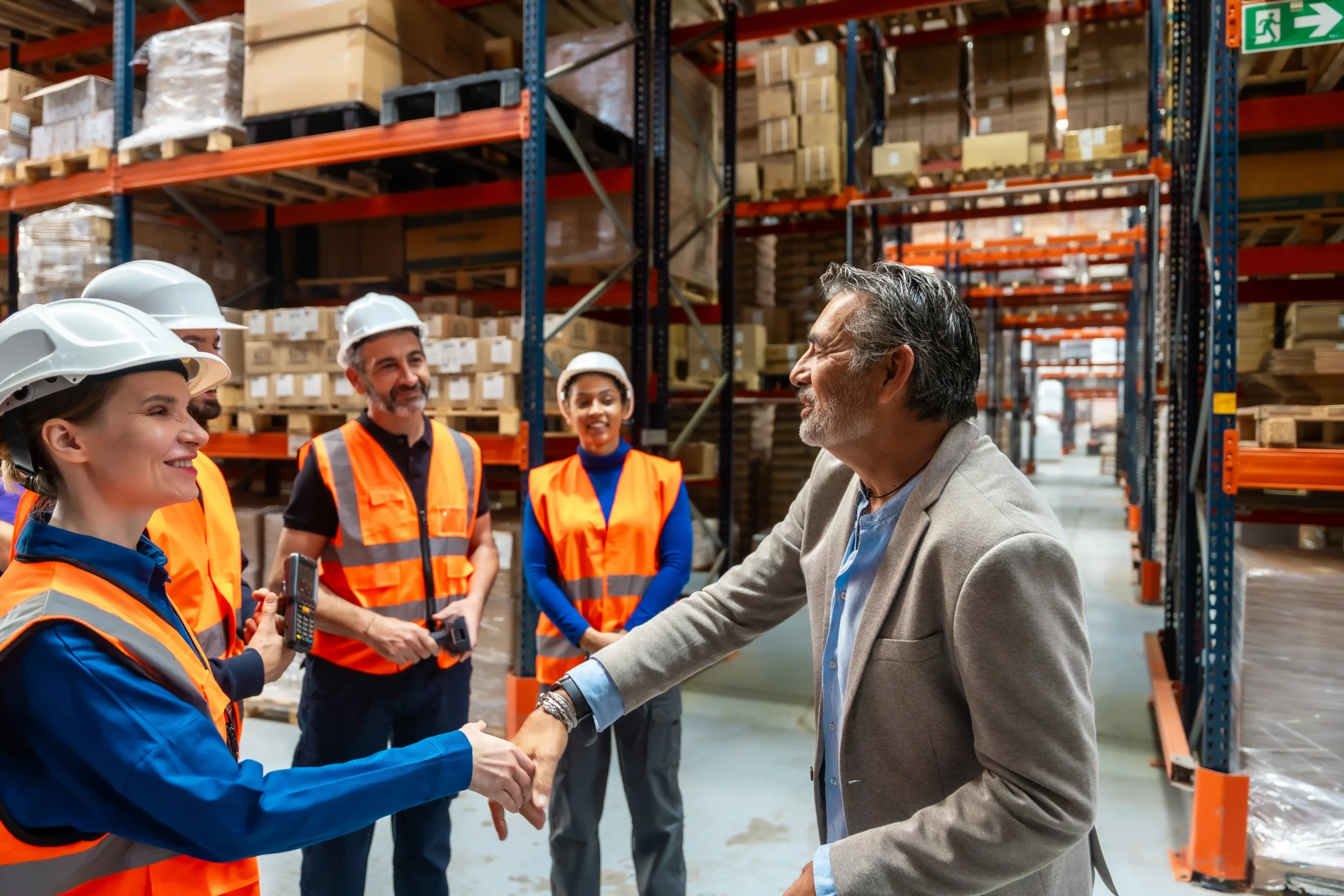 A warehouse storage company manager shaking hands with a client during a facility walkthrough, representing strong service, trust, and partnership.
