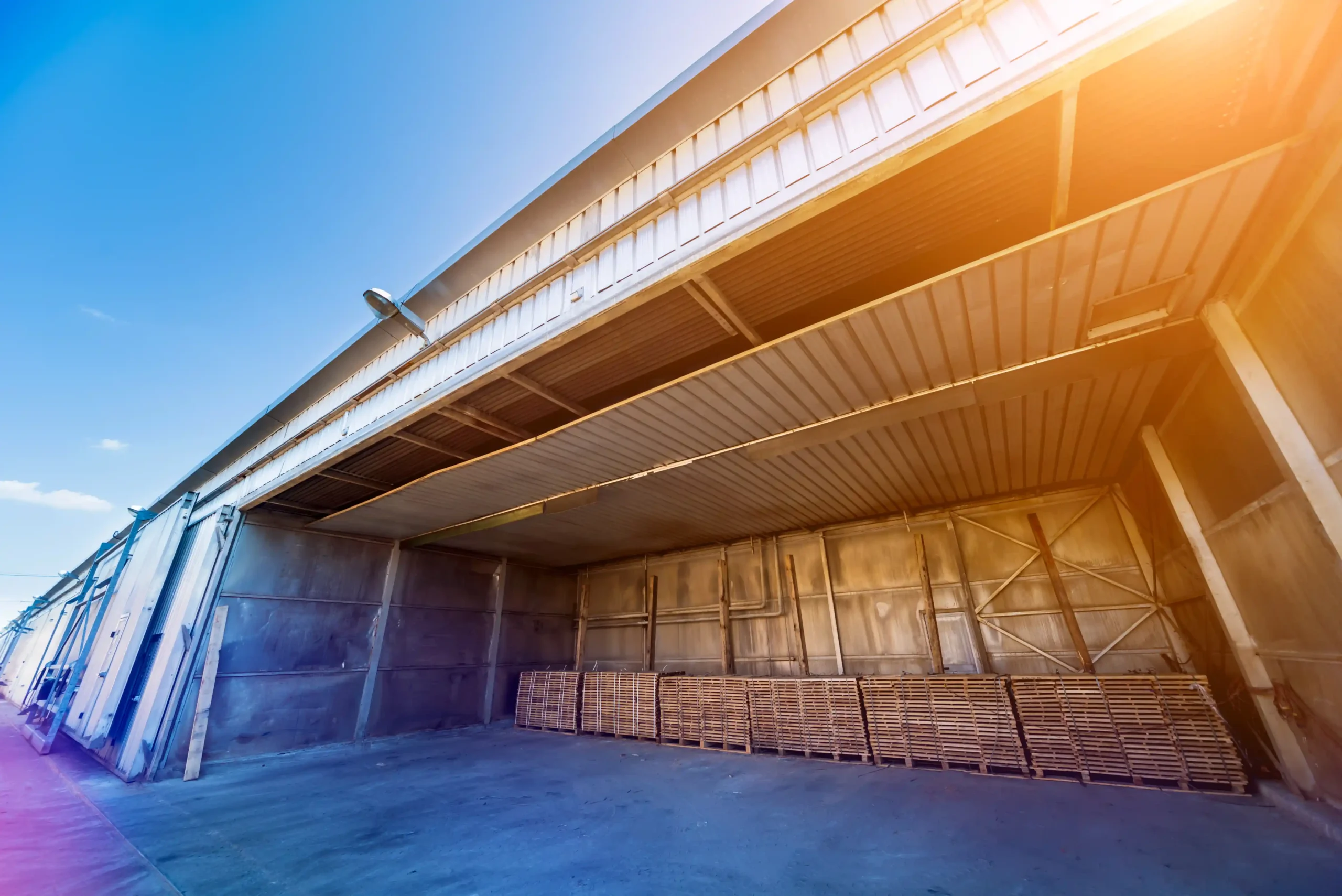 Open loading area of warehouse storage buildings with stacked pallets ready for distribution and storage.