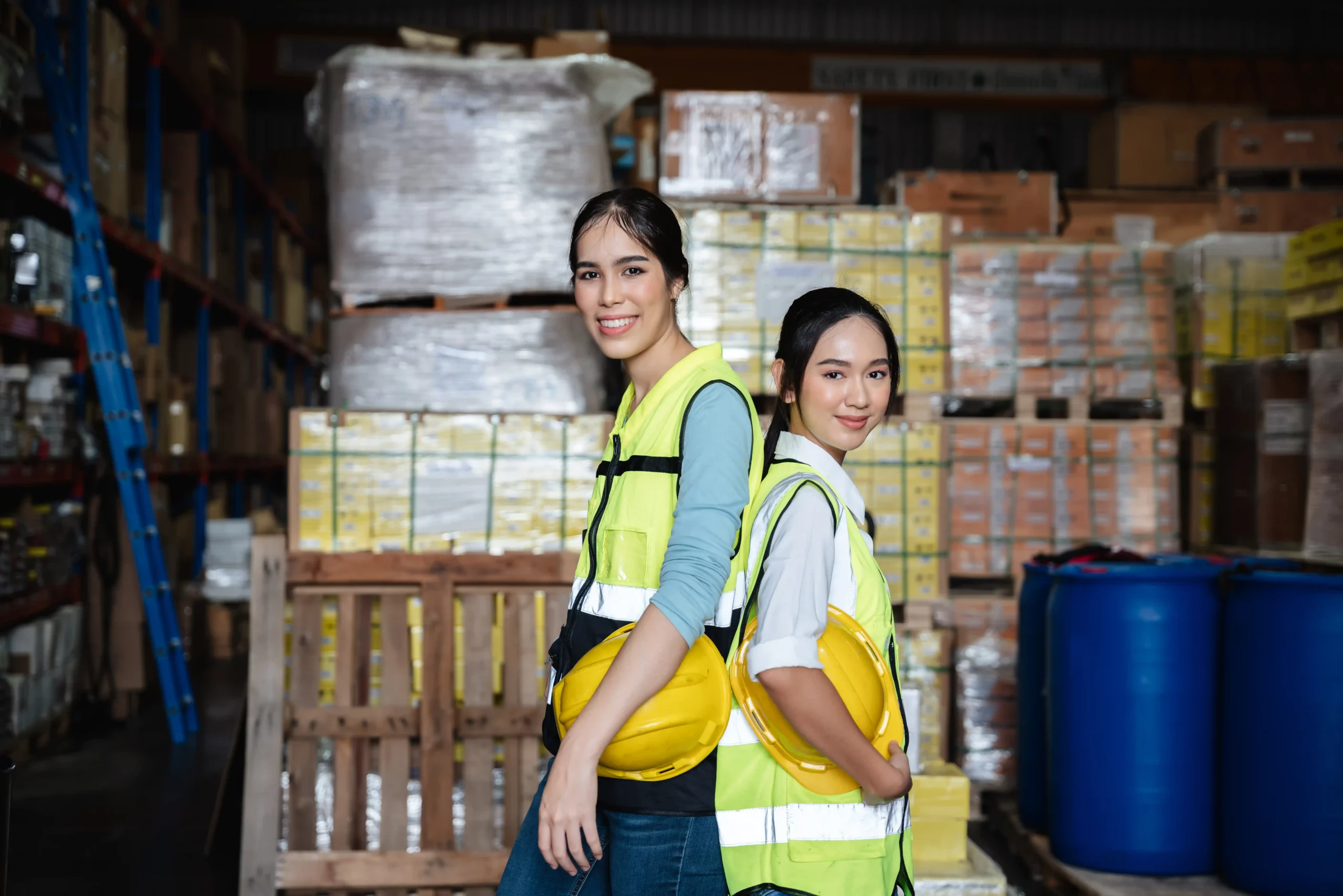 Two warehouse employees standing in front of stocked shelves, representing efficient operations supported by bins for warehouse storage.