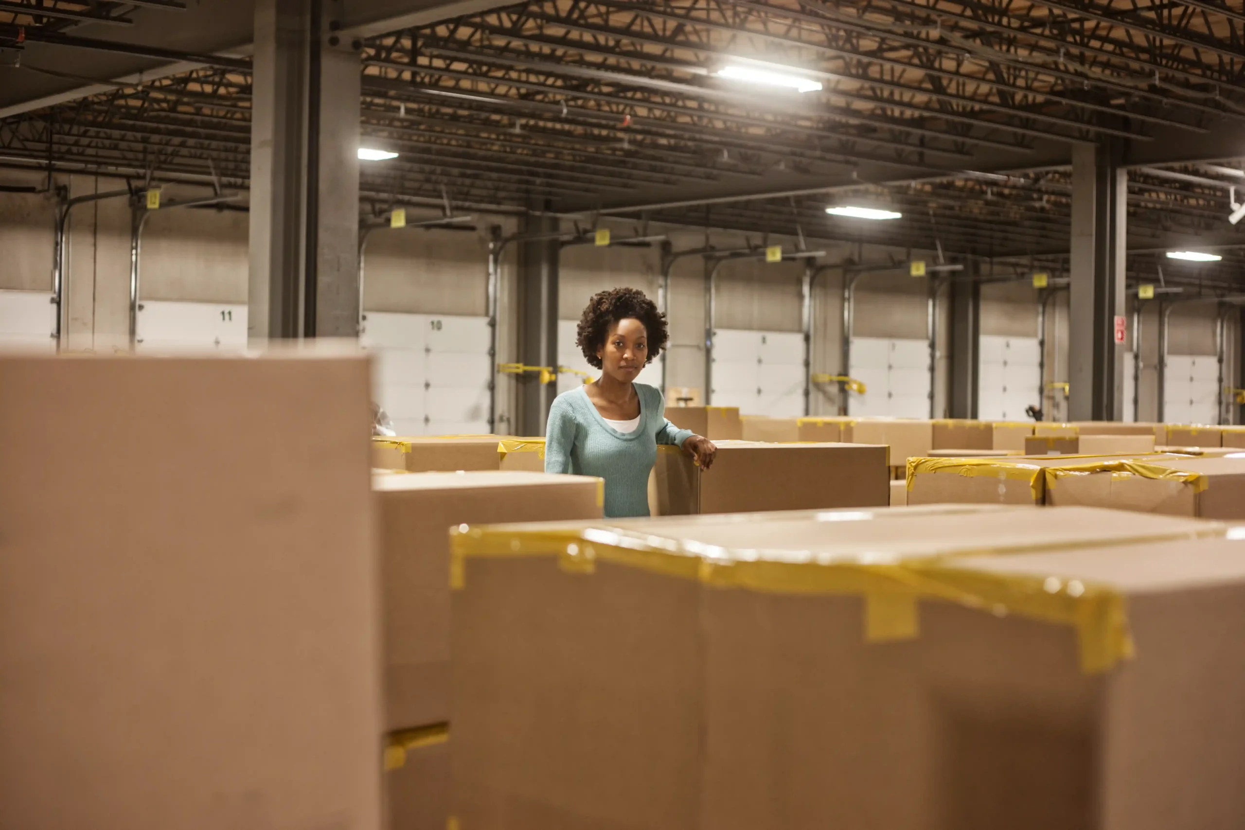Warehouse supervisor evaluating packed boxes in a large clothing warehouse storage environment.