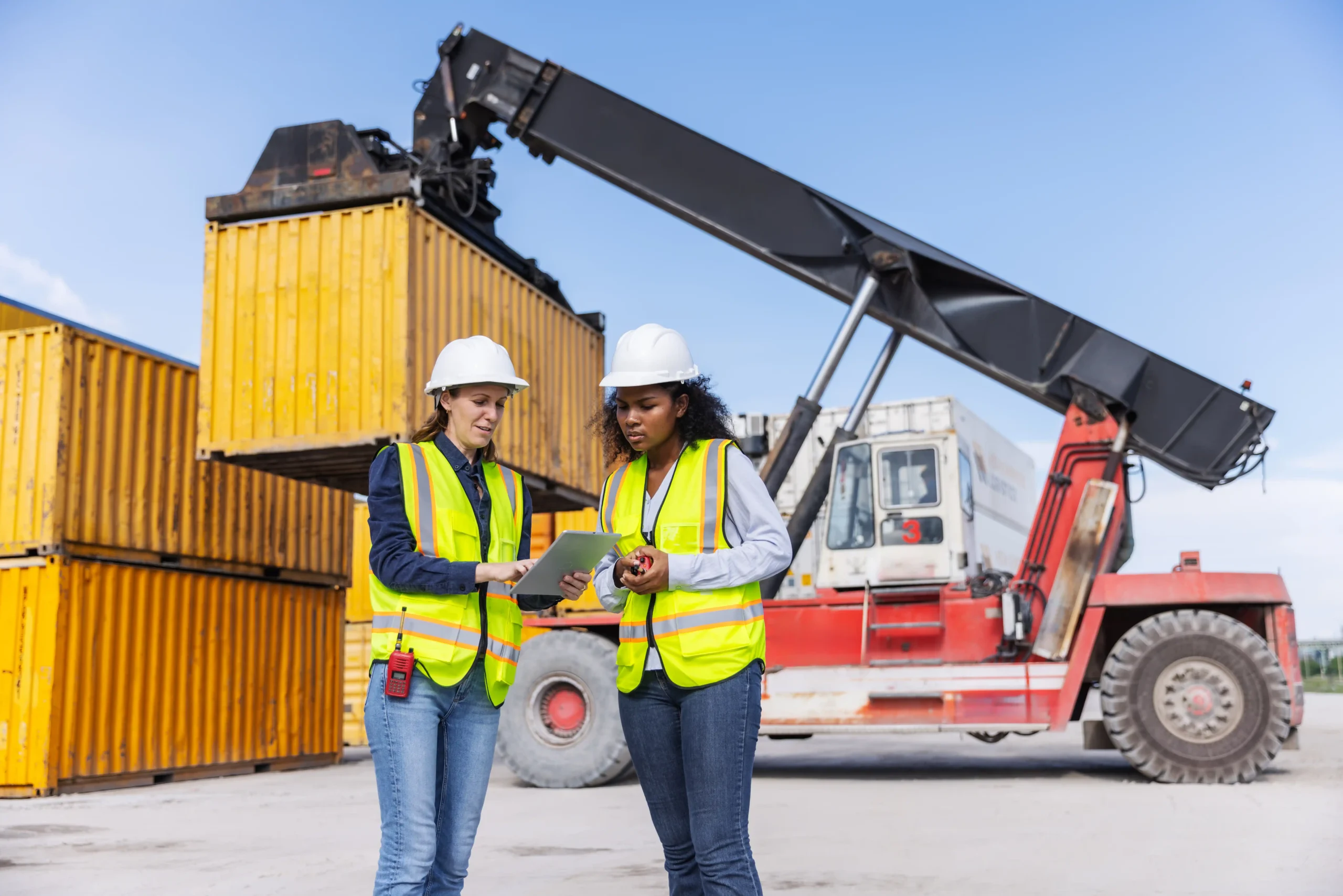 Warehouse professionals coordinating container handling equipment as part of global warehouse and logistics operations