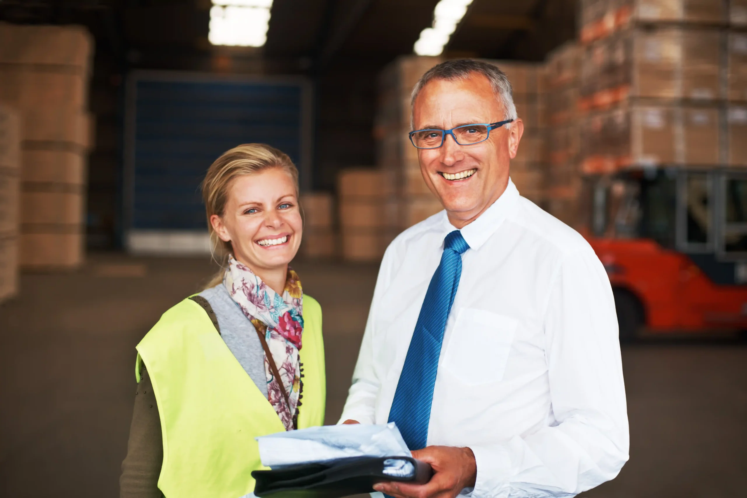 Smiling warehouse professionals standing inside a distribution center, representing teamwork and confidence supported by warehouse storage insurance.