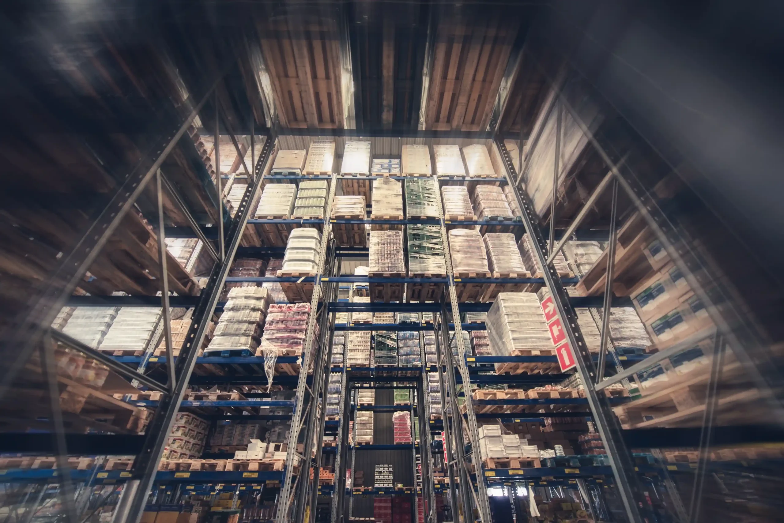 Tall vertical warehouse storage rack system filled with pallets and bulk goods in an industrial storage facility.