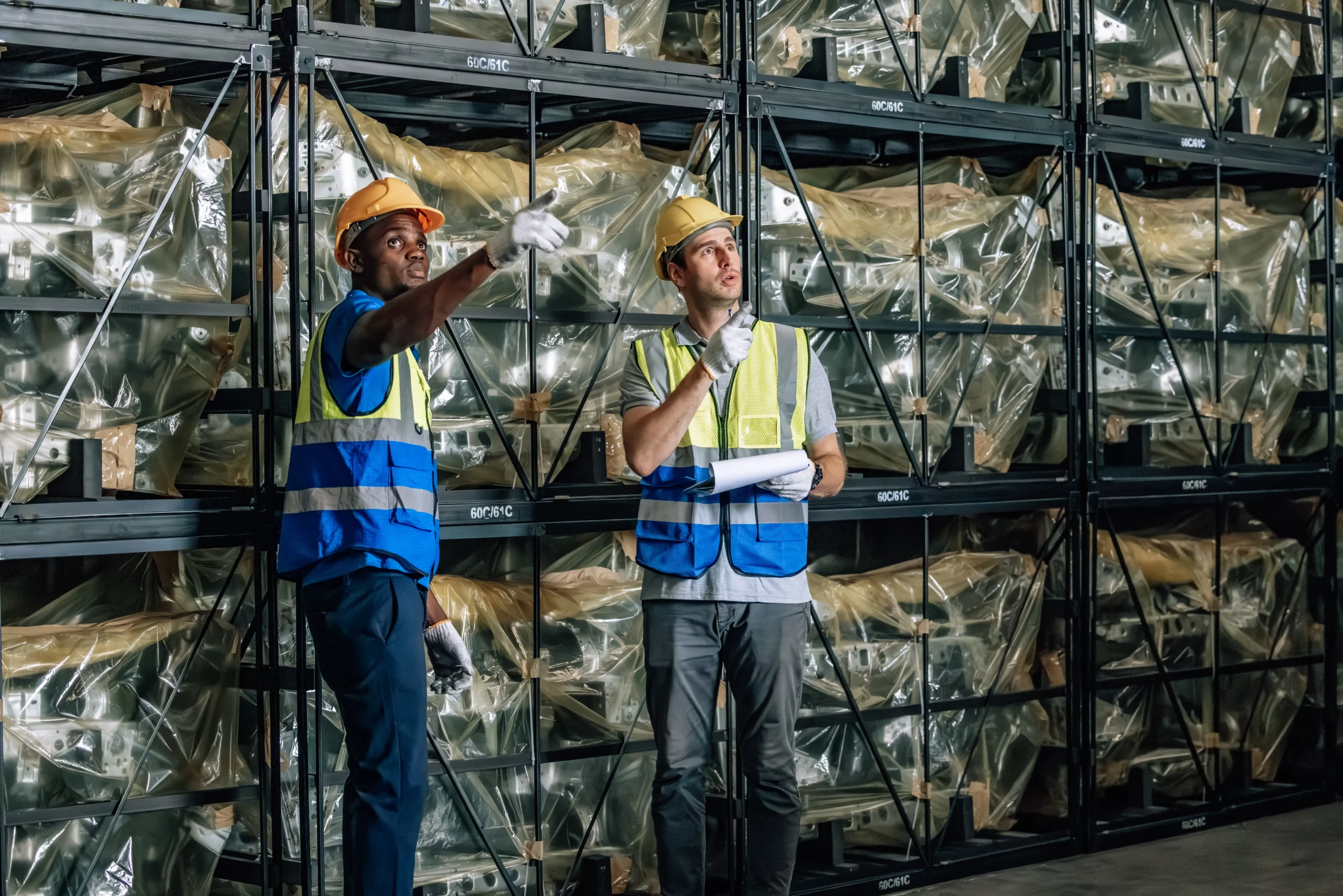 Warehouse staff inspecting automotive materials stored on metal racks for warehouse storage.