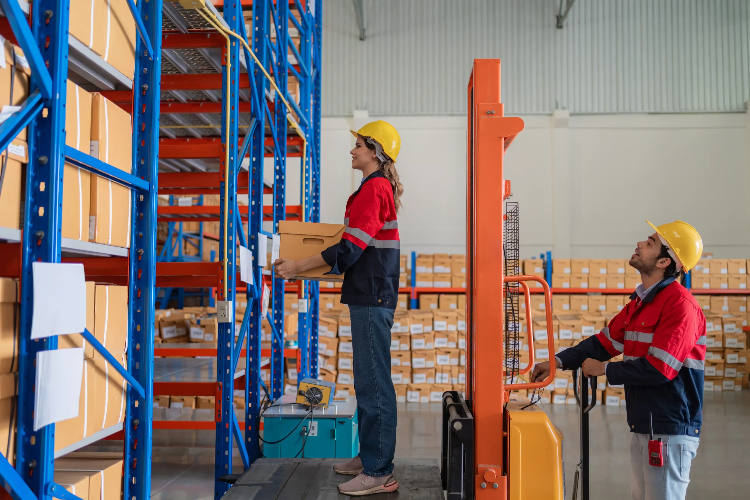 Two workers placing boxes on shelving inside an active warehouse storage and distribution center.