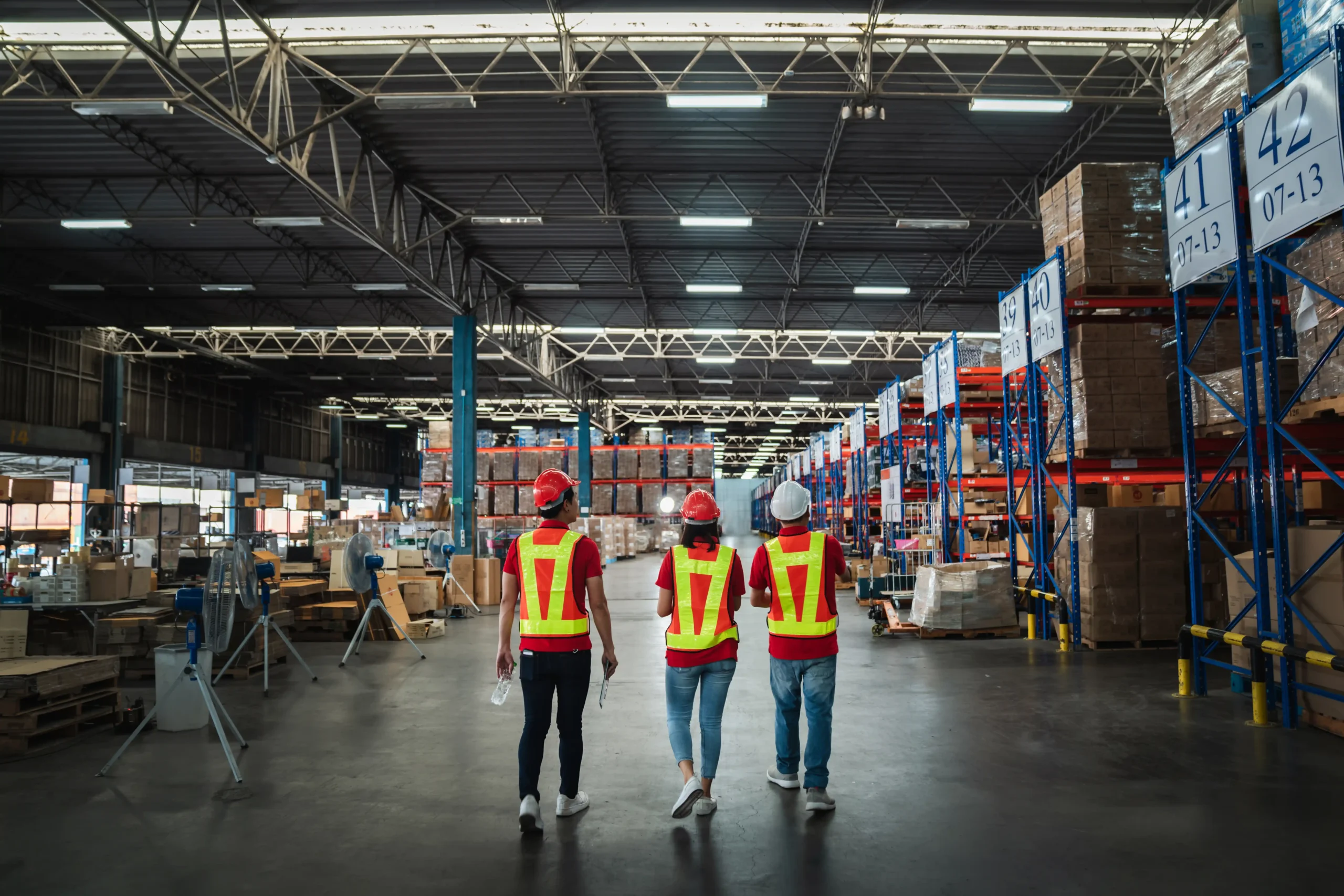Warehouse staff walking through aisles lined with pallet racking and other types of warehouse storage setups.