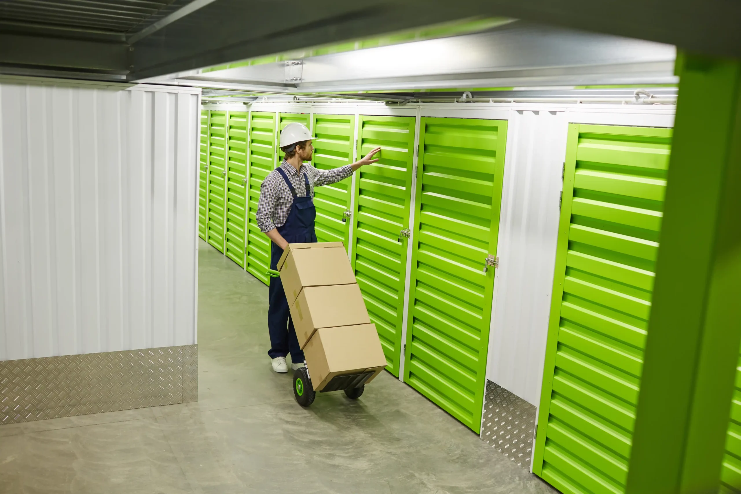 Warehouse employee moving boxes through a hallway of storage units, highlighting the importance of commercial storage insurance for stored equipment and goods.