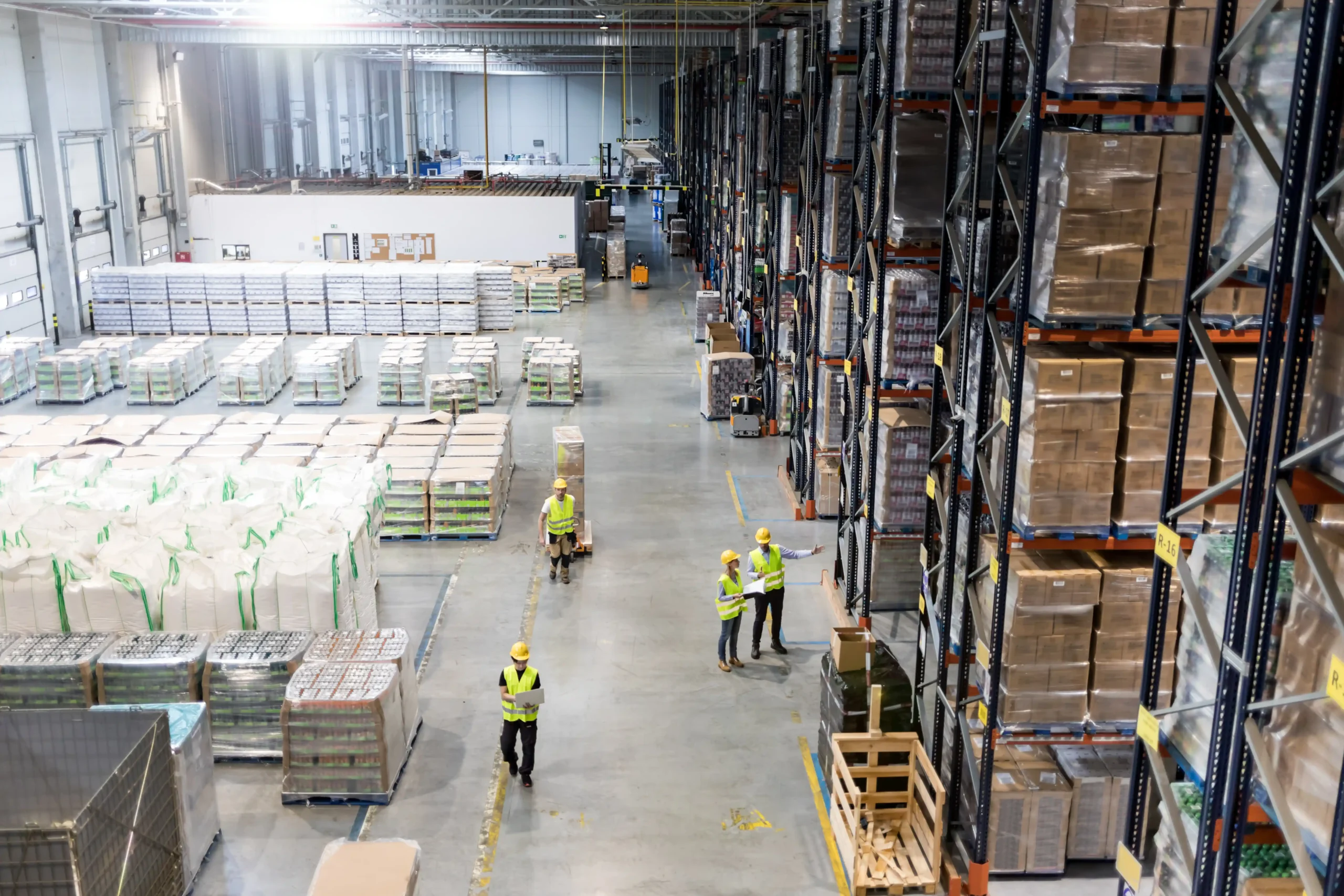Aerial view of active warehouse zones with workers, pallet racks, and staged inventory